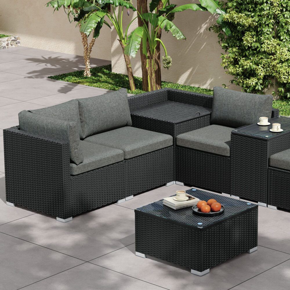 Black wicker corner loveseat with grey cushions and glass-topped storage coffee table