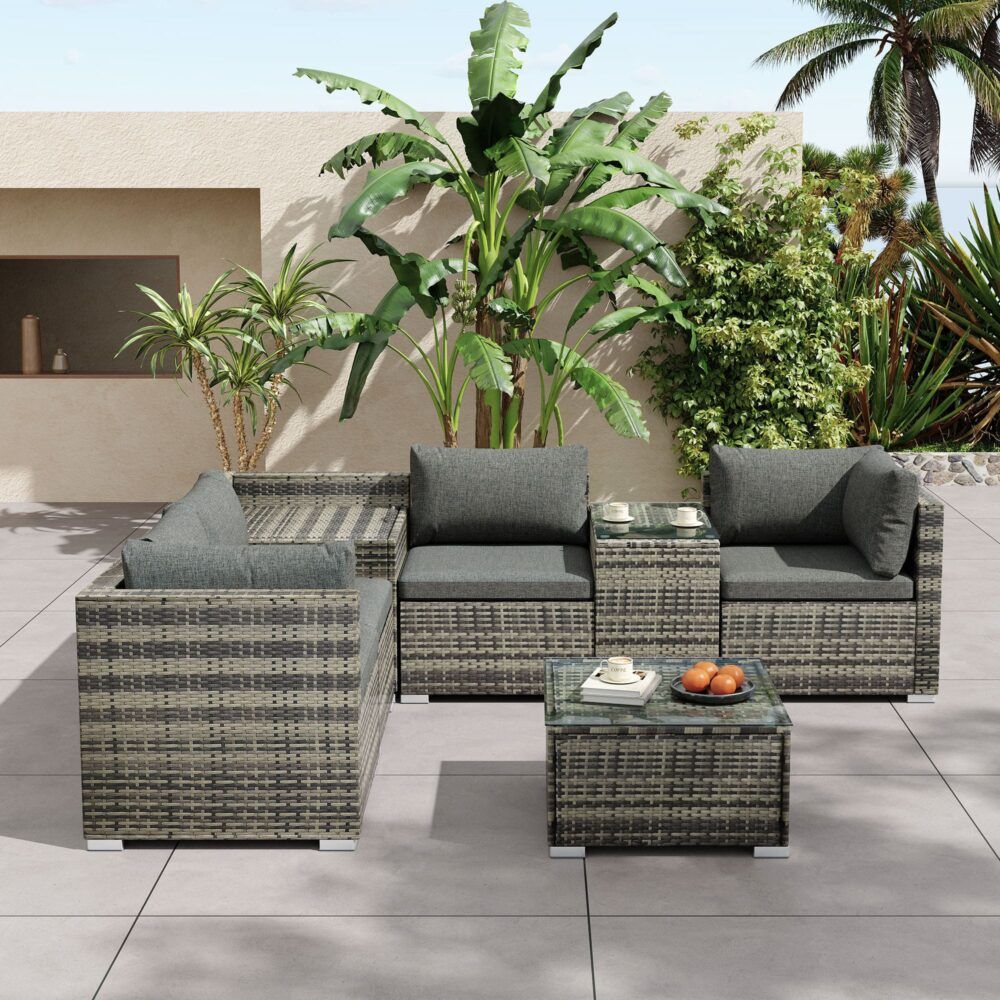 Grey outdoor wicker lounge seating set with corner section, armchairs, and glass-top coffee table