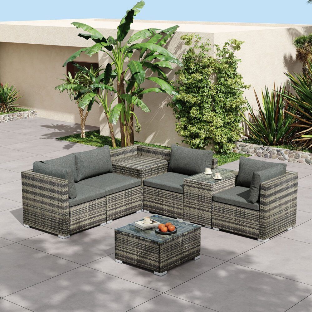 Grey outdoor wicker corner lounge set with cushioned arm seats and glass-top coffee table