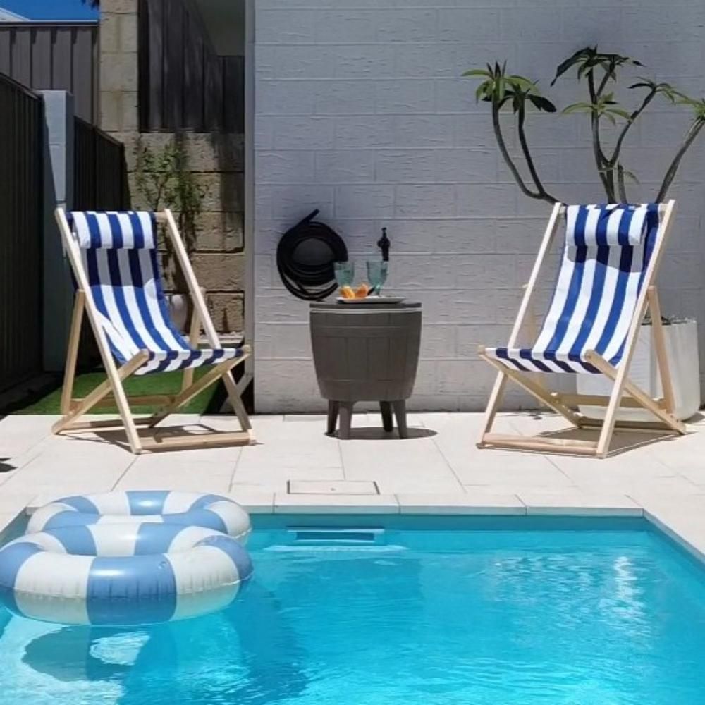 Taupe cooler table with round lid and raised legs beside a pool deck.
