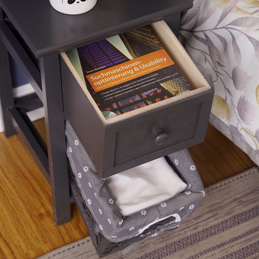 Grey drawer bedside table with open wicker basket and folded fabric inside.
