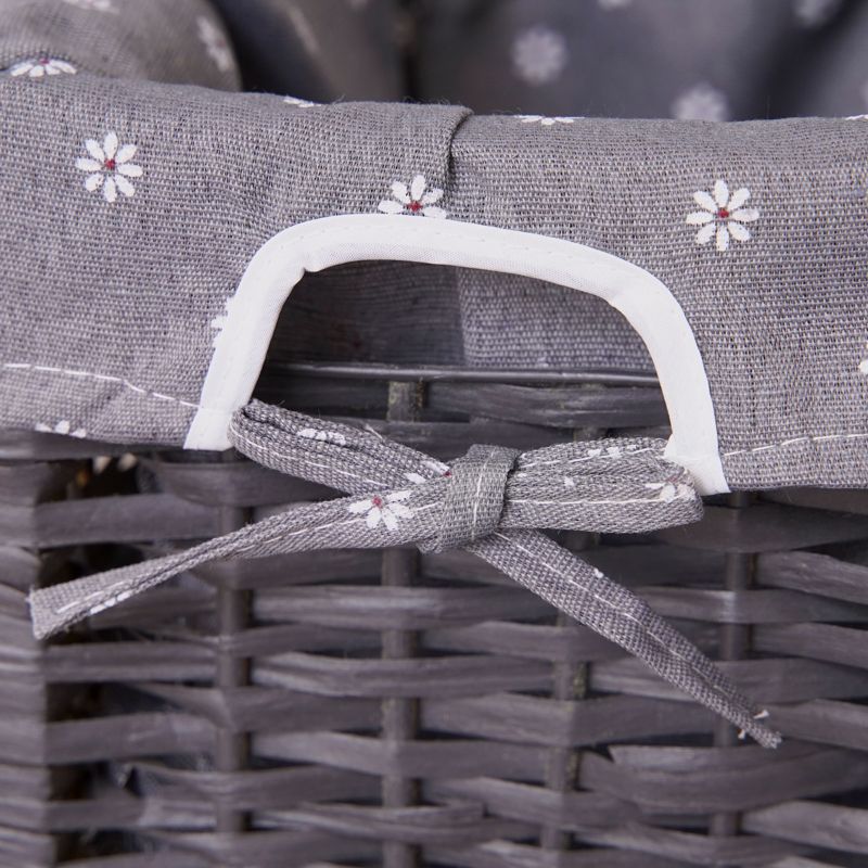 Wicker basket with grey fabric liner and white floral pattern, tied closed with ribbon.