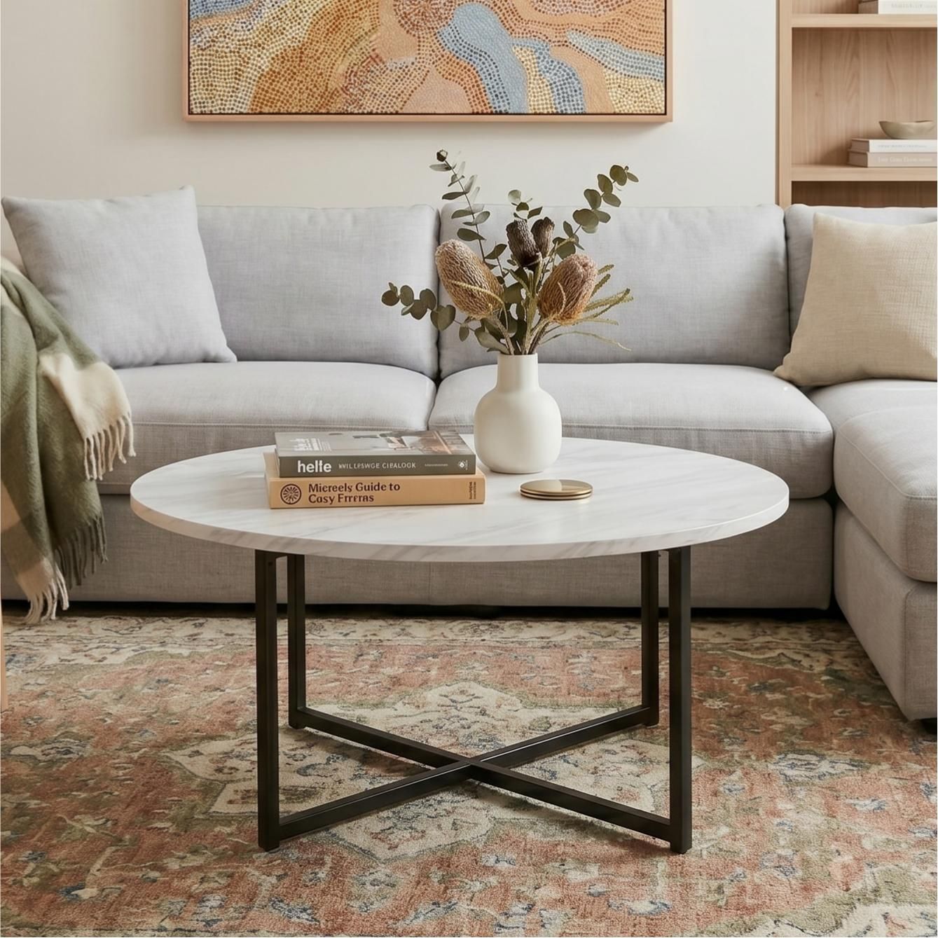 Round coffee table with white marble-effect top and black X-cross legs