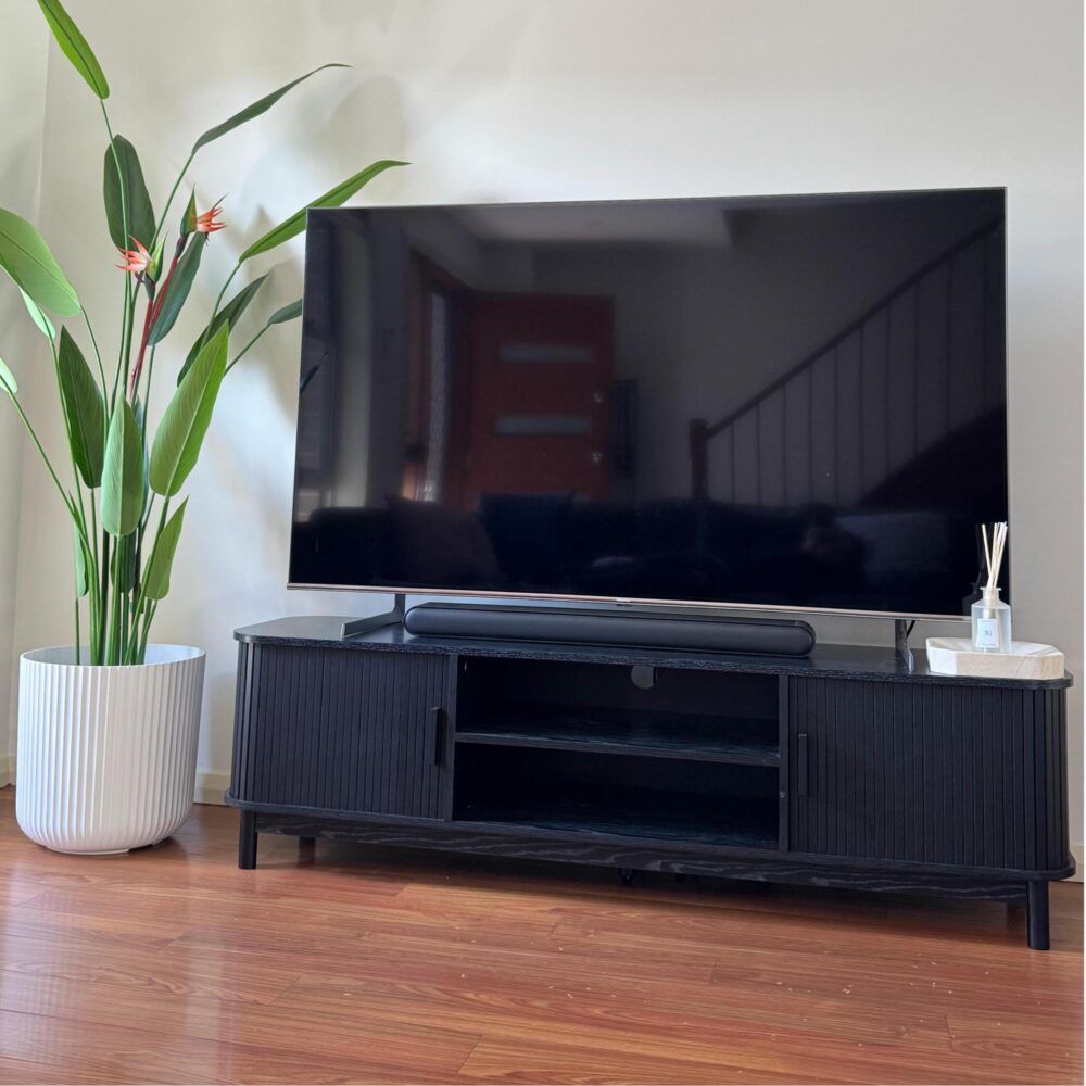 Ribbed black TV console with two doors and a lower media storage shelf