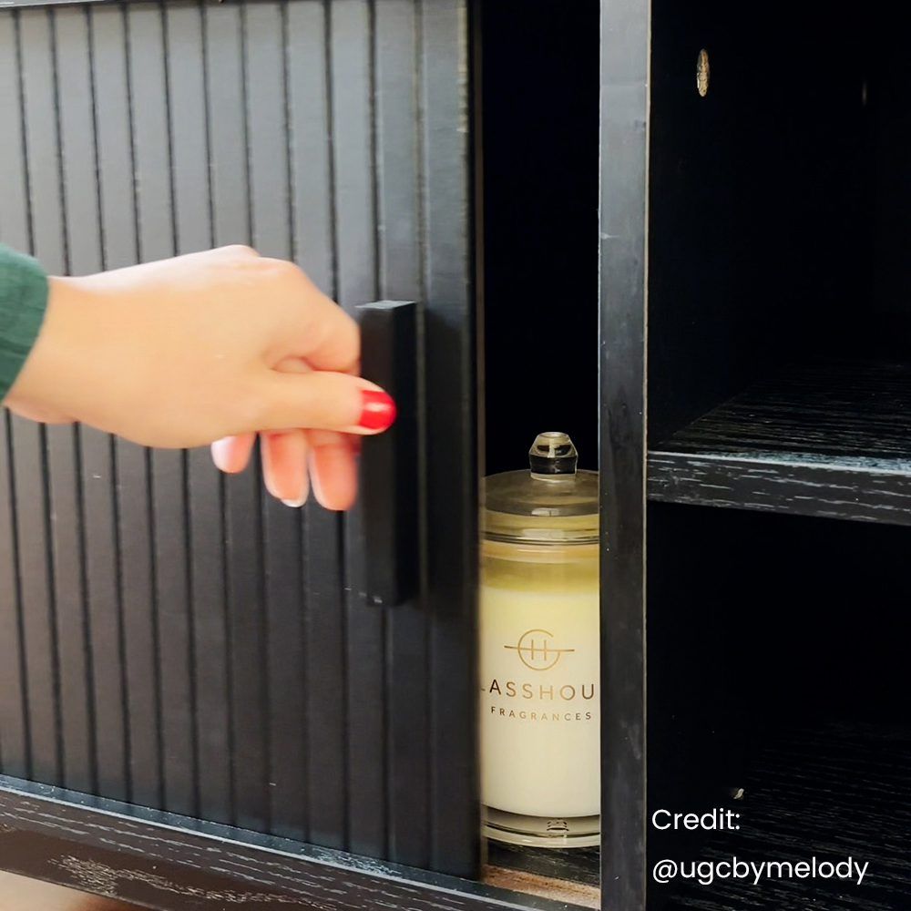 Black entertainment unit door opening to reveal a bottle on the interior shelf