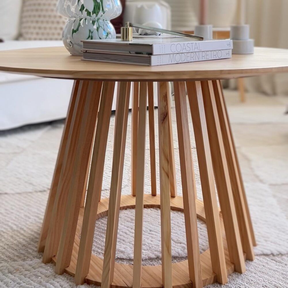 Round natural wood coffee table with vertical slat legs, side view