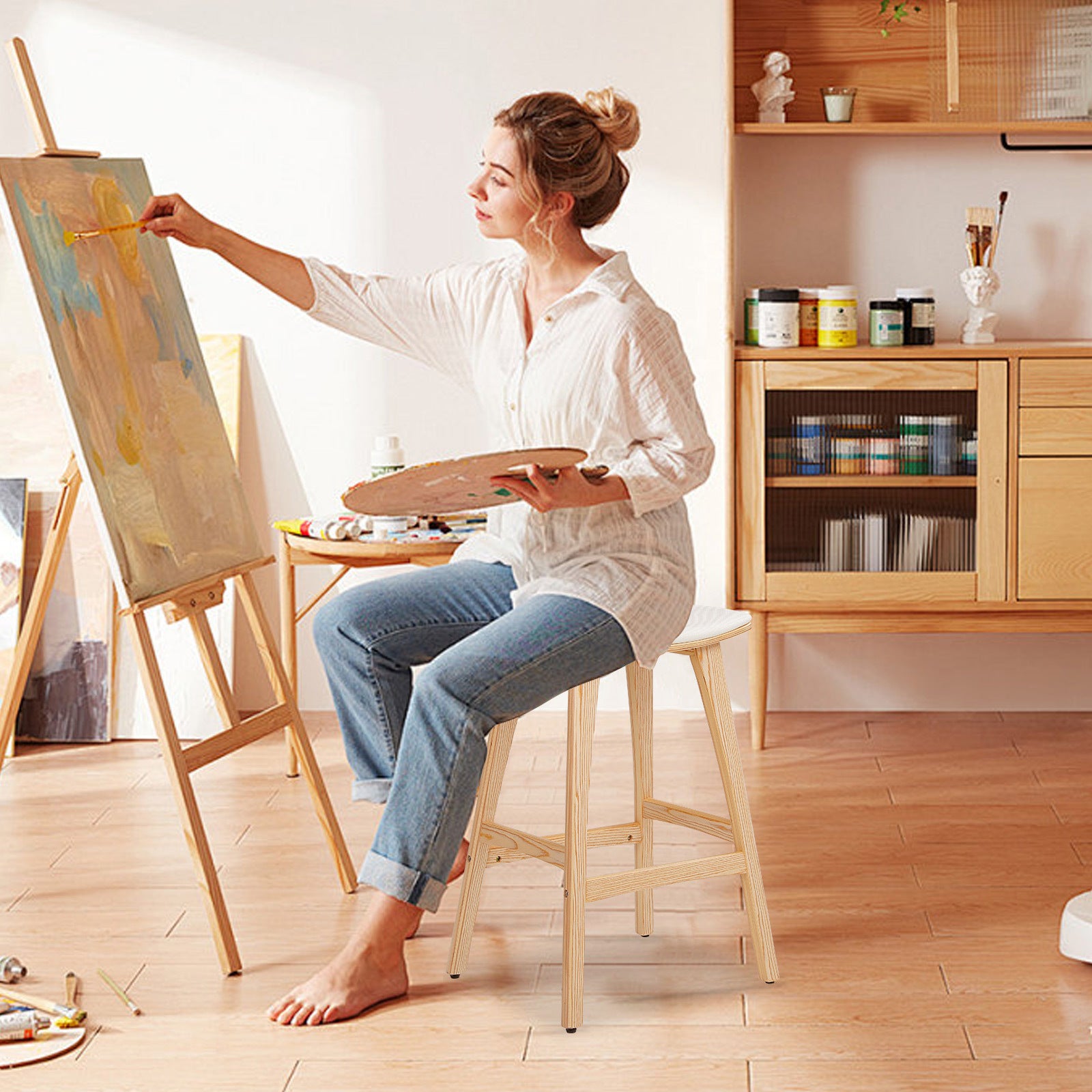 Beige padded wooden bar stool with footrest bar, occupied by a seated person