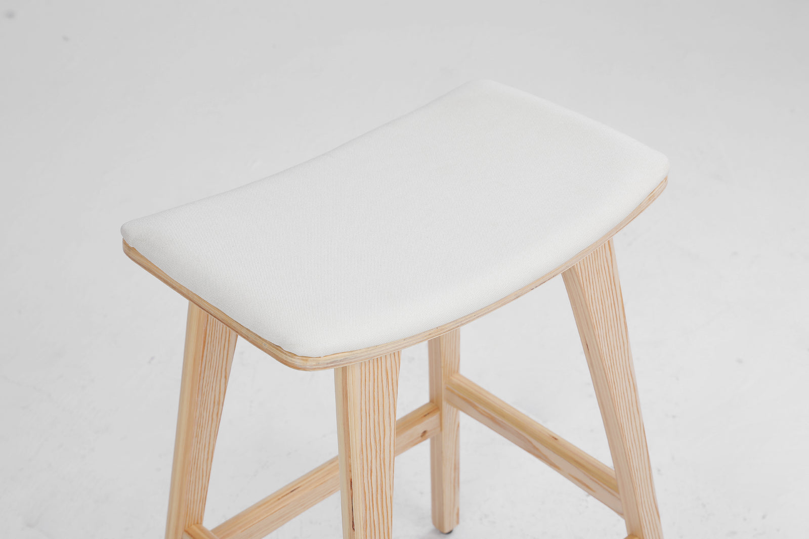 Beige padded bar stool with light wood frame and rounded cushioned seat