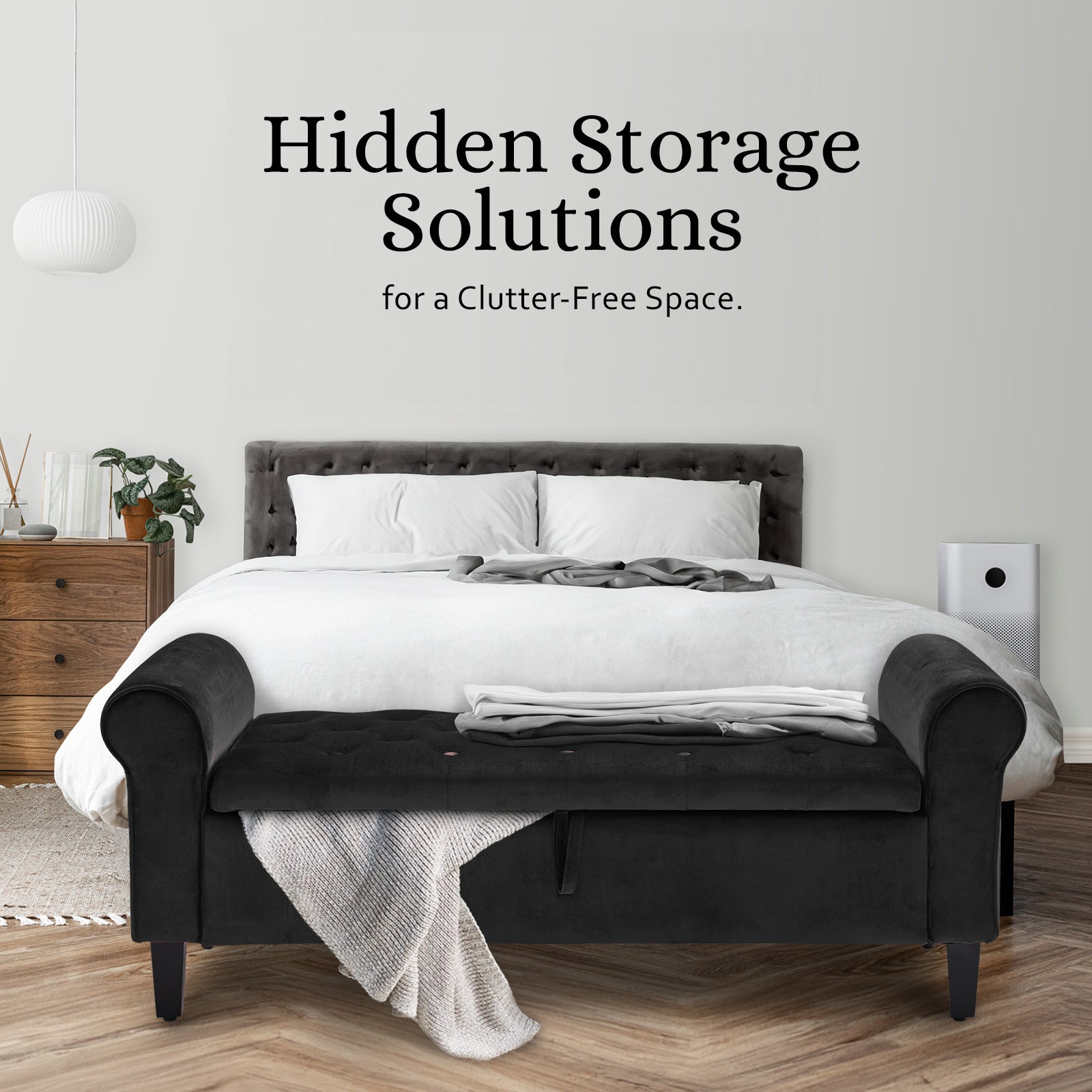 Black velvet storage ottoman bench with rolled arms and tufted seat, front view.
