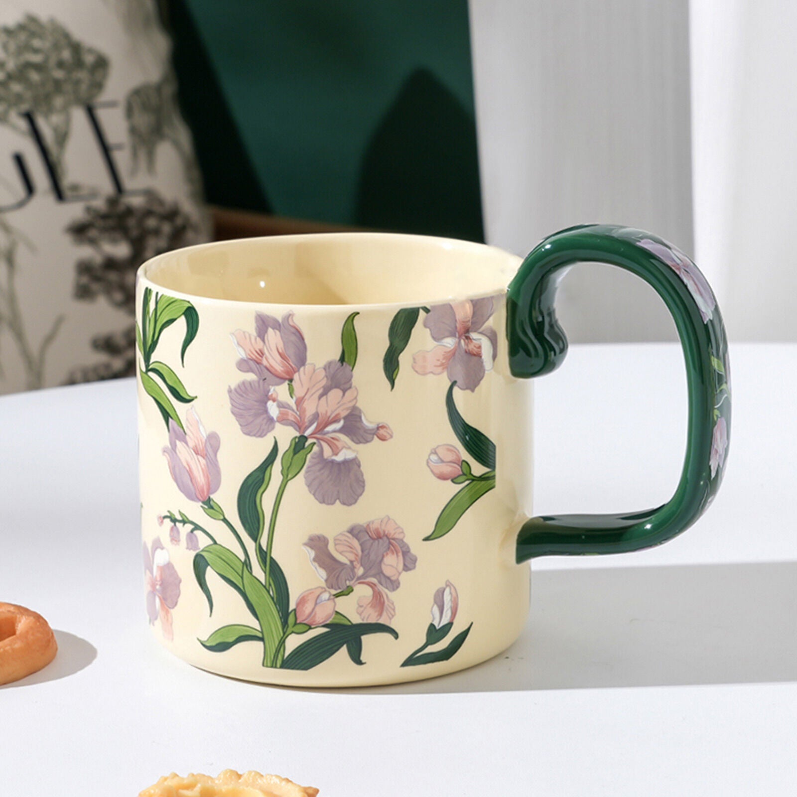 Ceramic porcelain mug with green handle and cream base with purple floral pattern