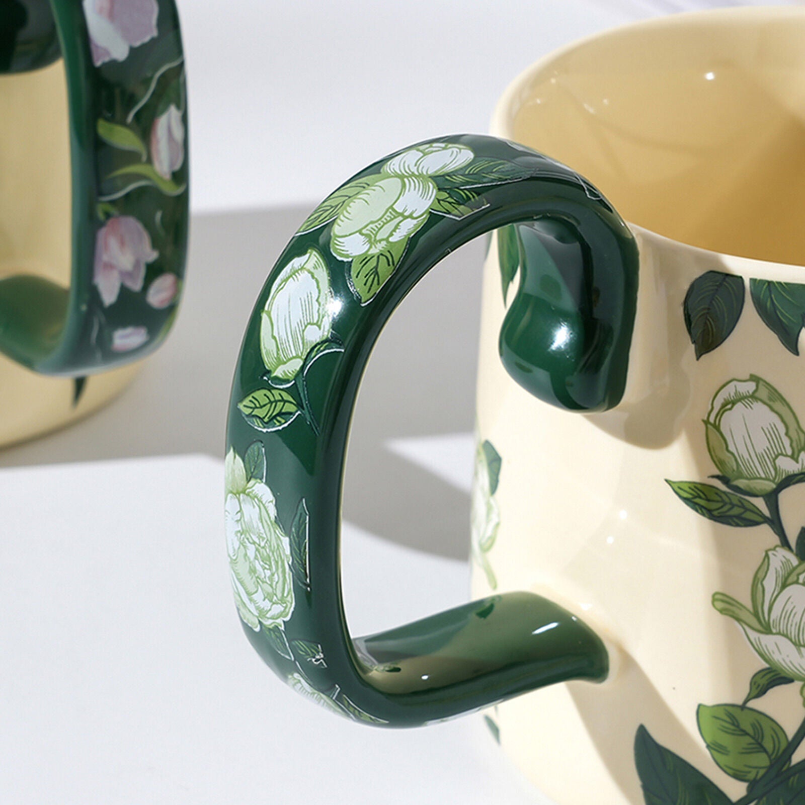 Ceramic porcelain mug handle with glossy green finish and floral body detail
