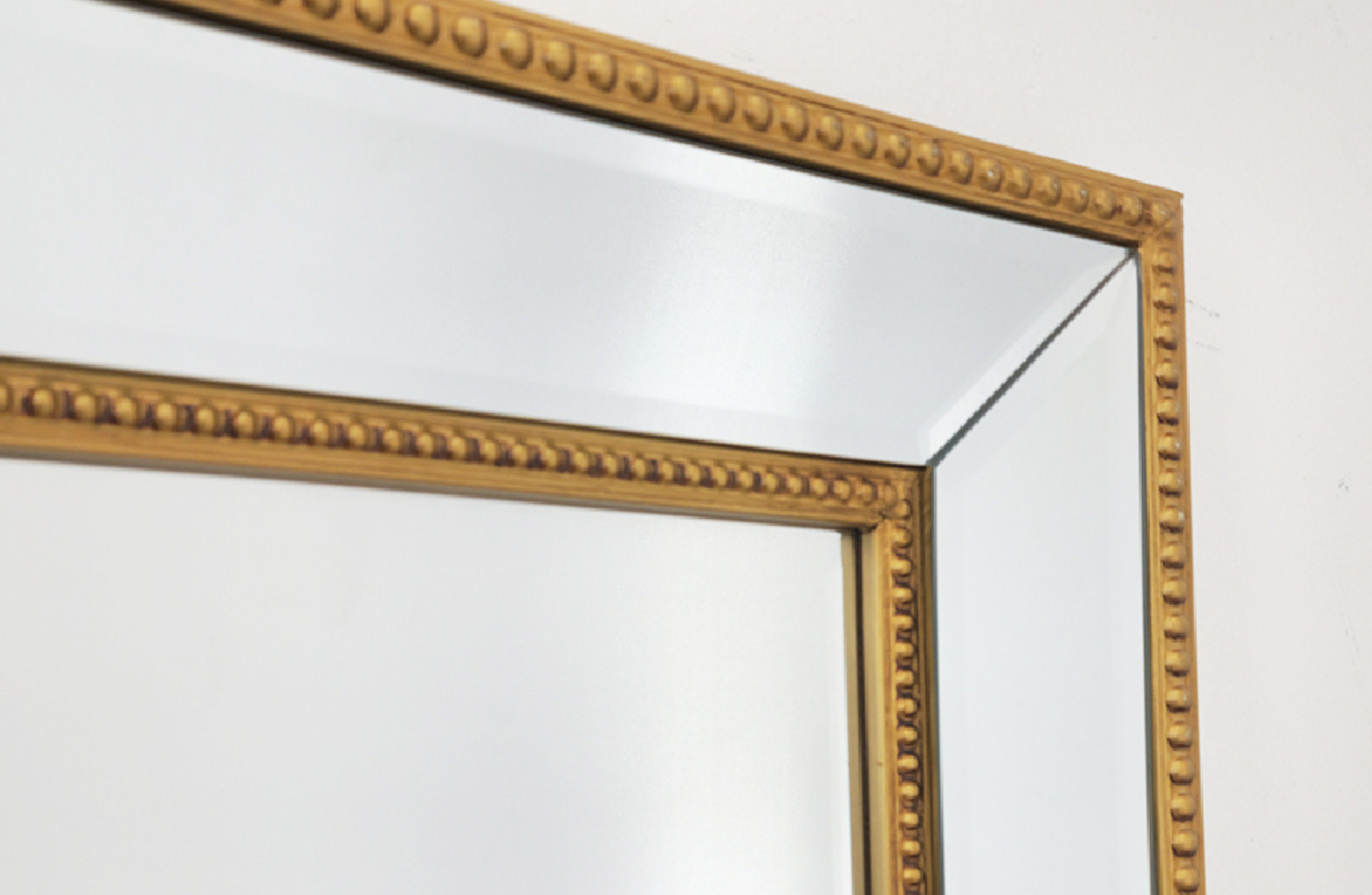 Gold beaded mirror frame detail with beveled glass edge
