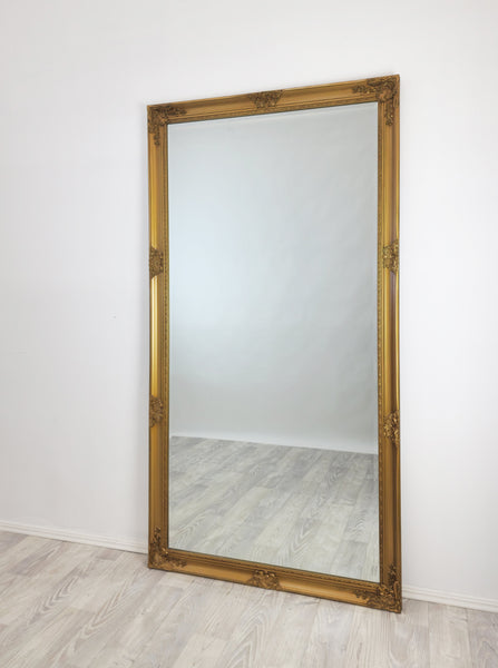 Full-length antique gold wall mirror with carved detailing around the frame
