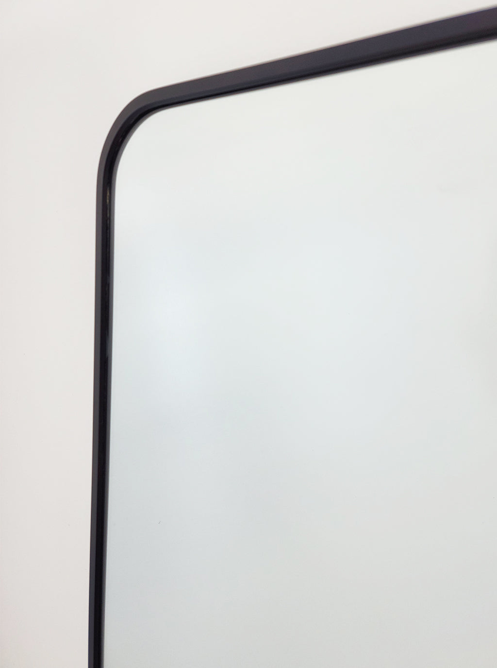Black metal mirror frame corner with smooth rounded profile
