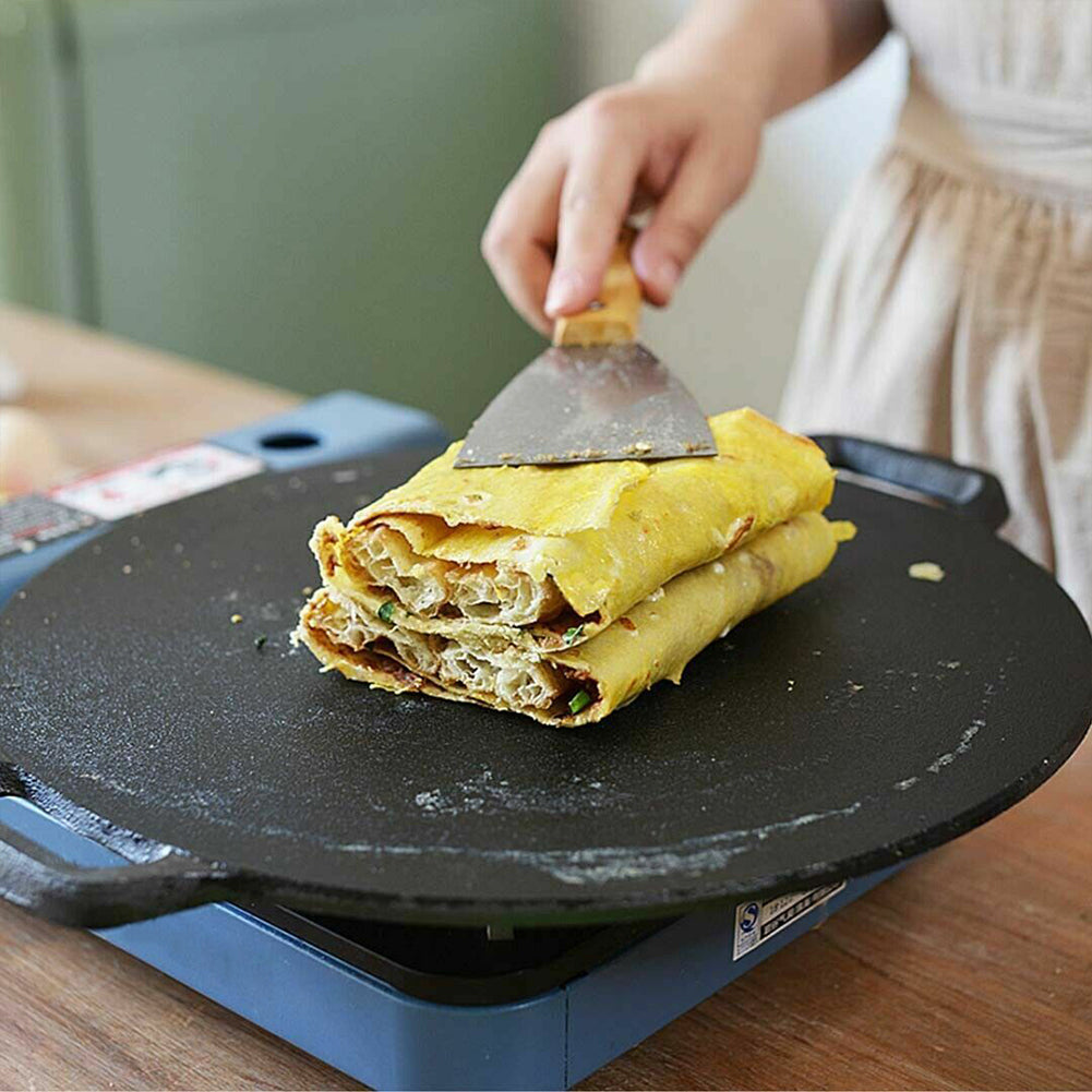 Seasoned cast iron crepes pan holding a folded crepe with visible layers