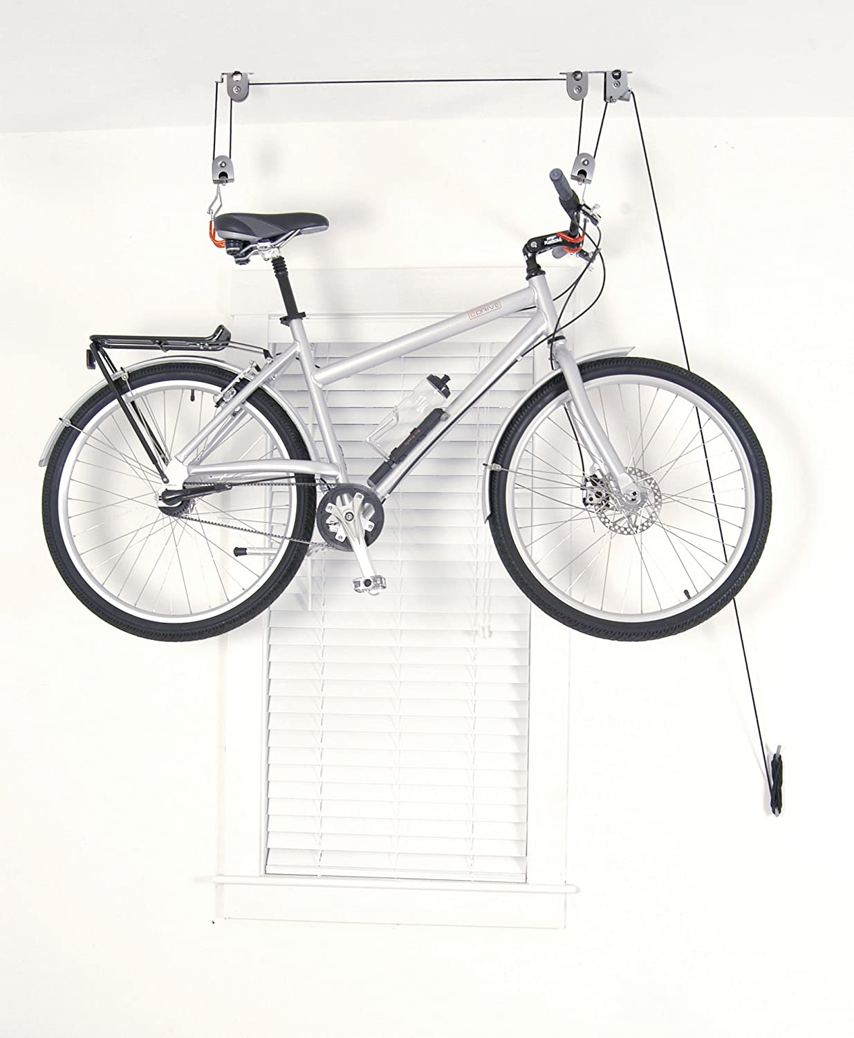 White bicycle suspended from a ceiling mount hoist with rope and pulley hooks
