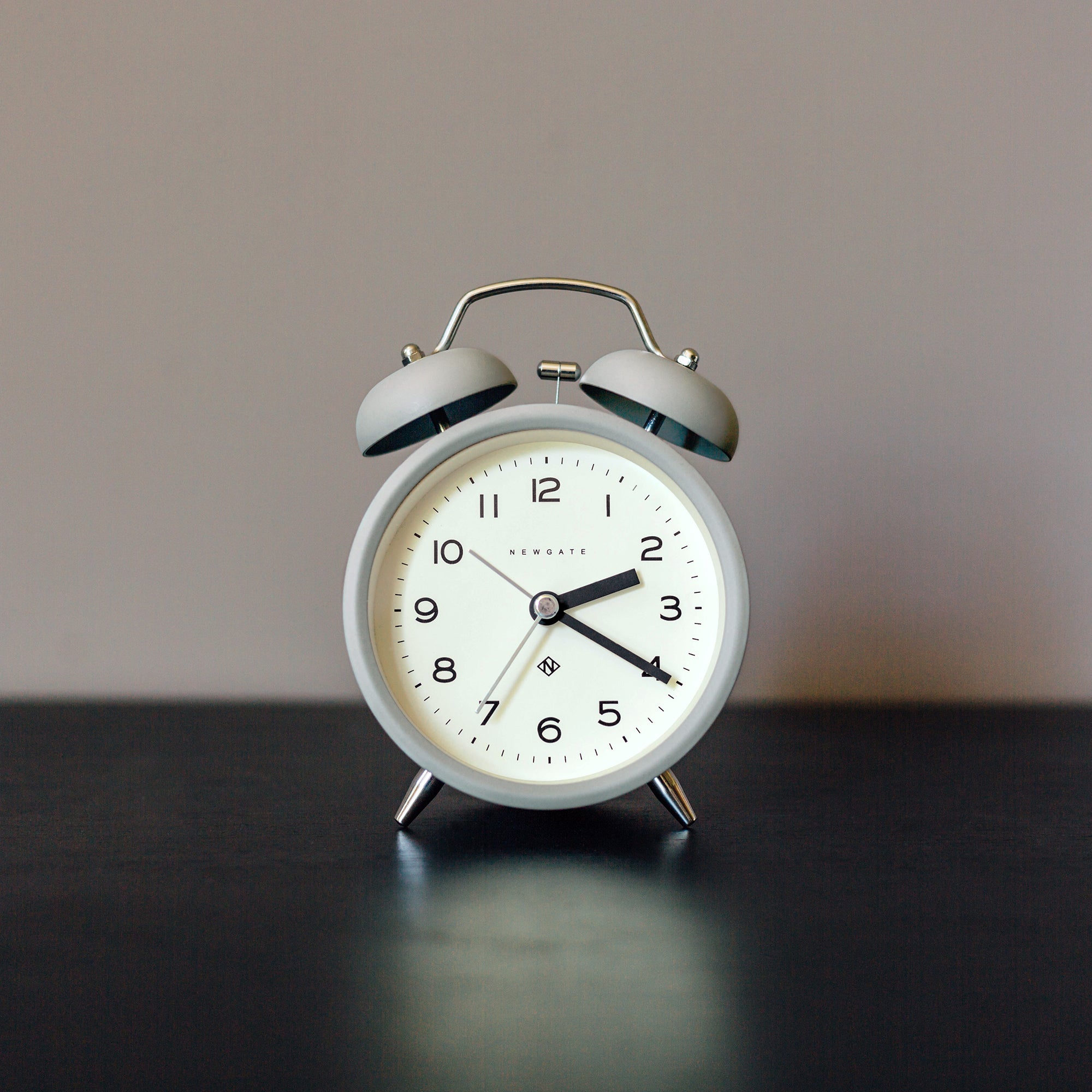 Matte grey twin-bell analog alarm clock with white dial and black hands
