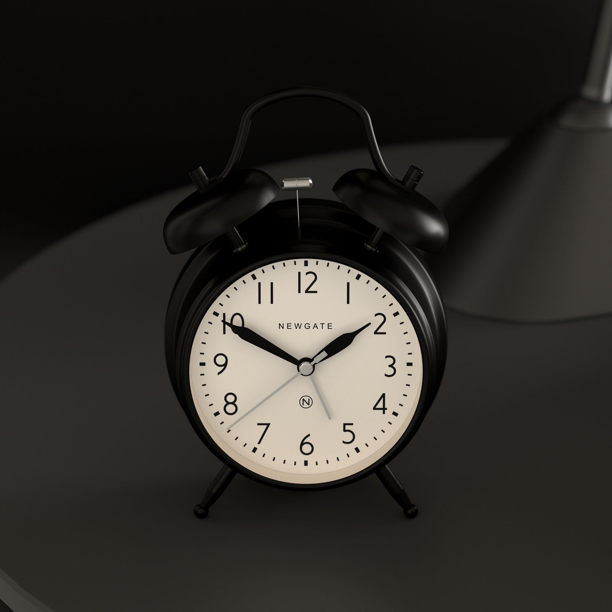 Matte black twin bell alarm clock close-up with white dial and black hour hands
