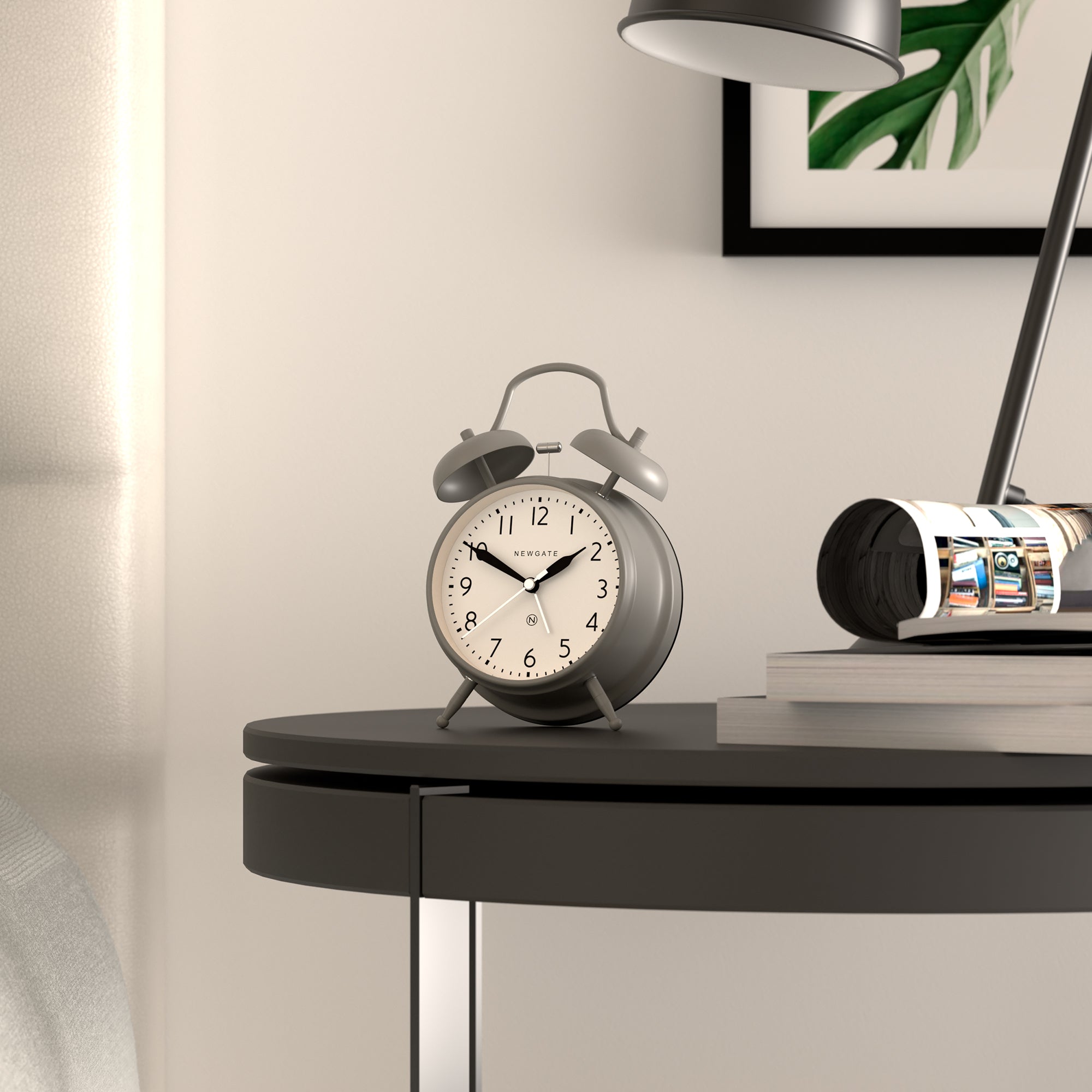 Grey twin-bell alarm clock on a tabletop shelf, round dial with black hands