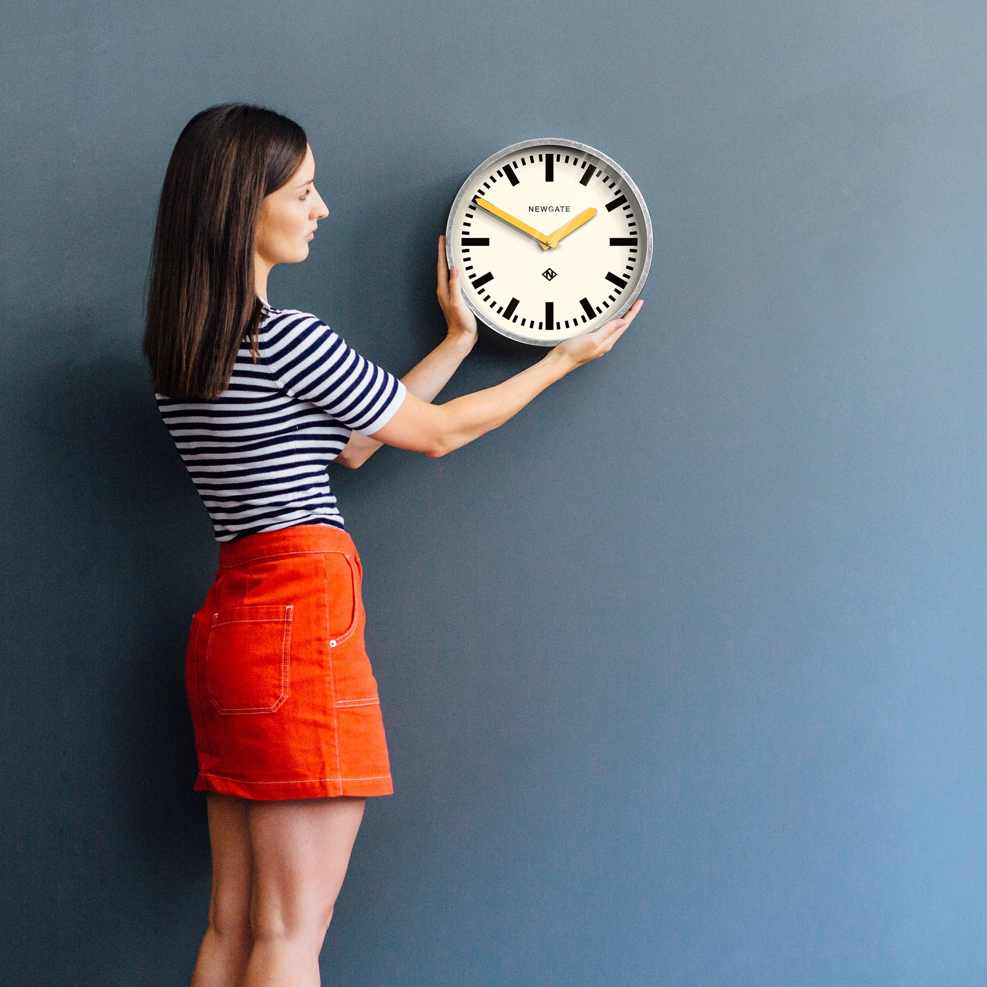 Round wall clock with cream dial, black markers and yellow hands