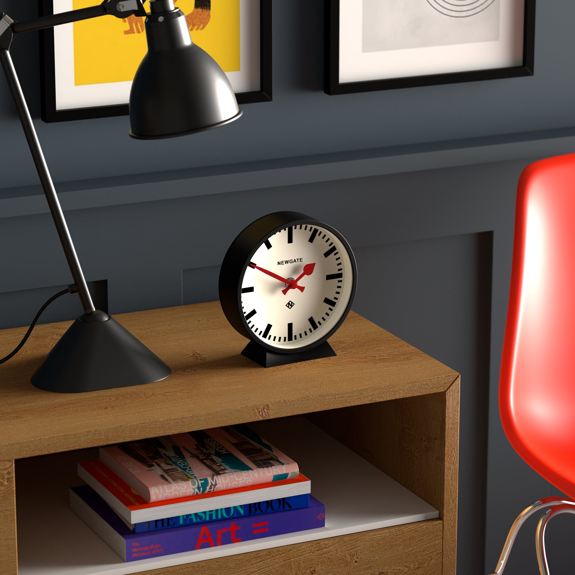 Side-on black mantel clock with white face and red hands on a stand