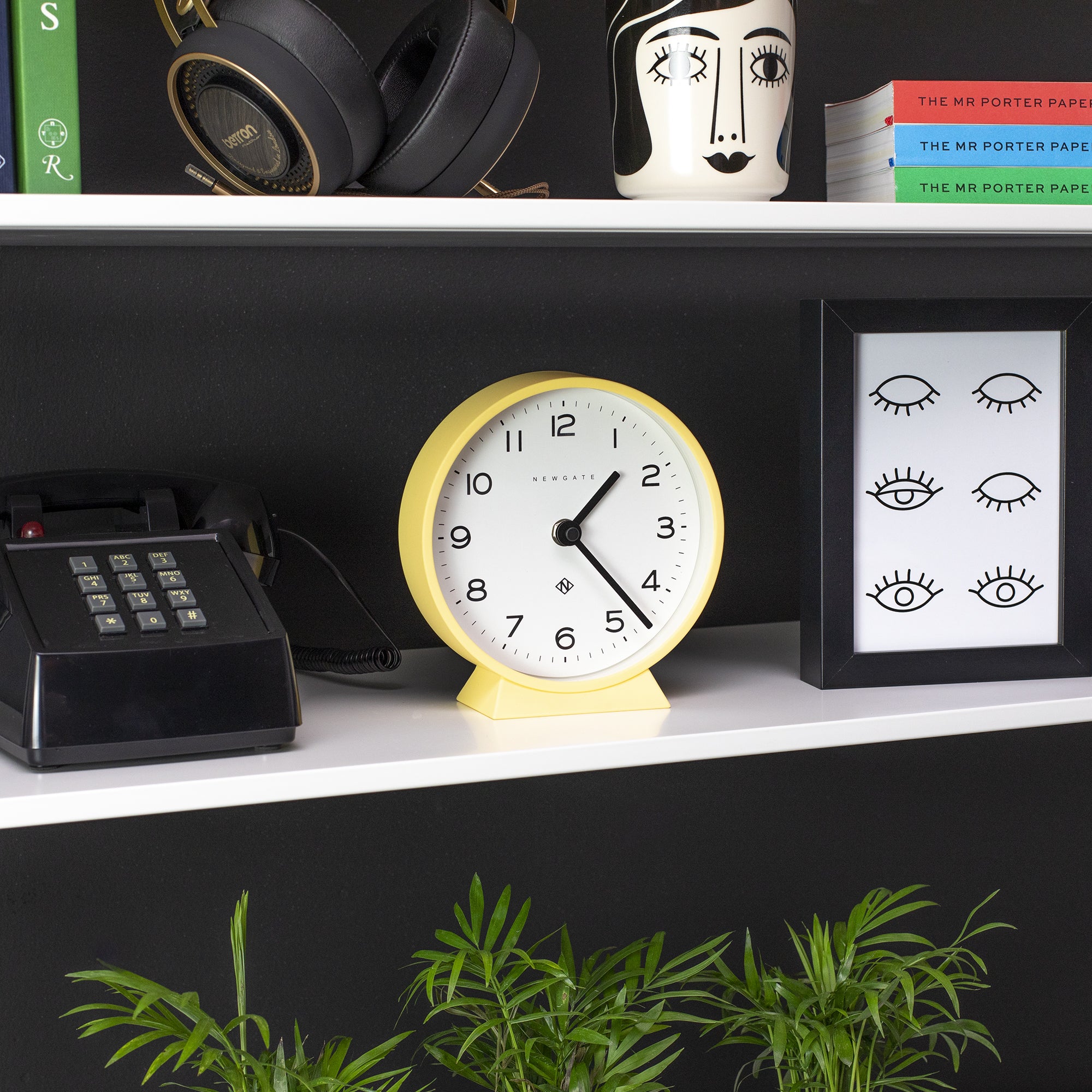 Yellow mantel clock on a shelf with white dial and black numerals
