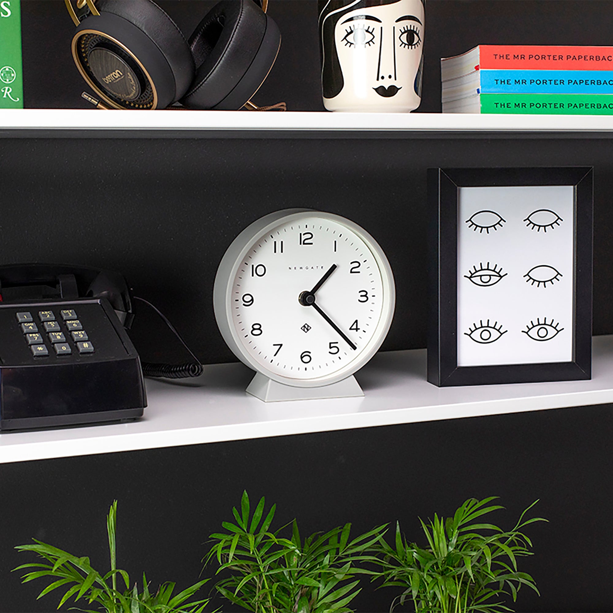 Grey mantel clock with white face and black hands, placed on a mantel