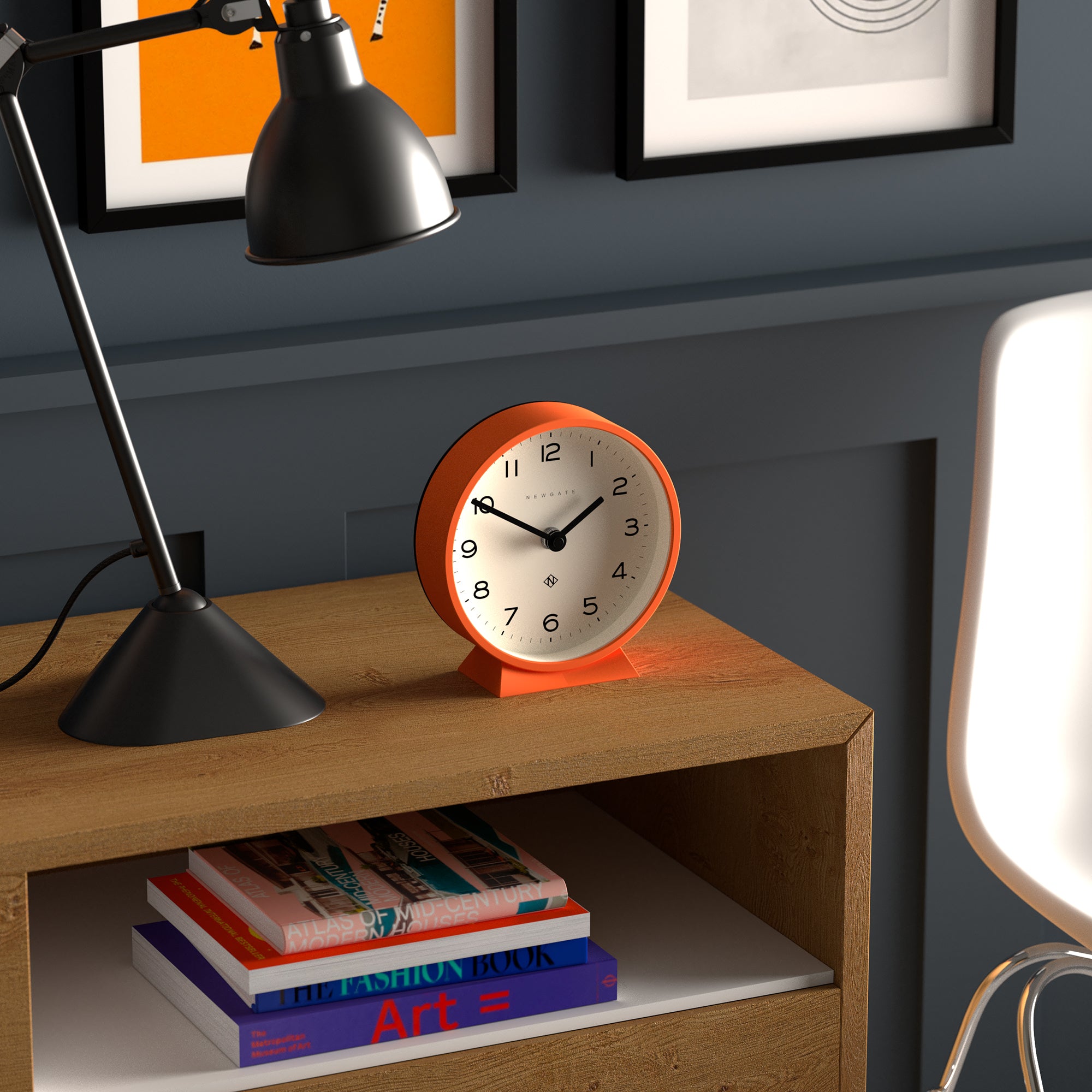 Orange mantel clock on wooden shelf, white dial with black hands and numbers