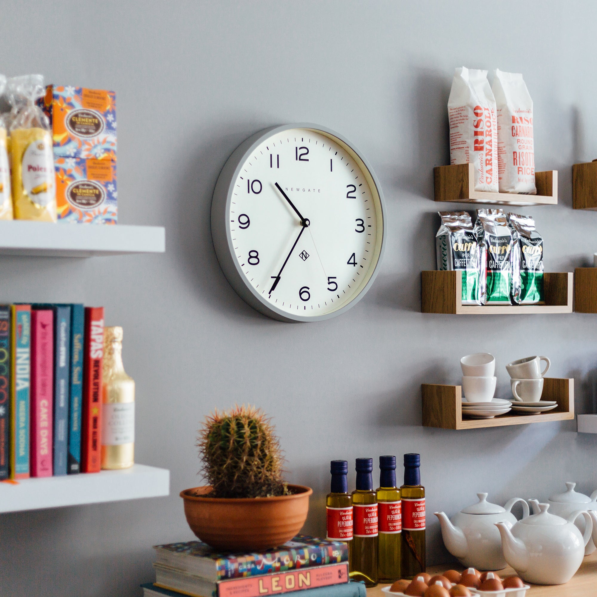 Round grey wall clock with white face, black numerals, and slim black hour hand