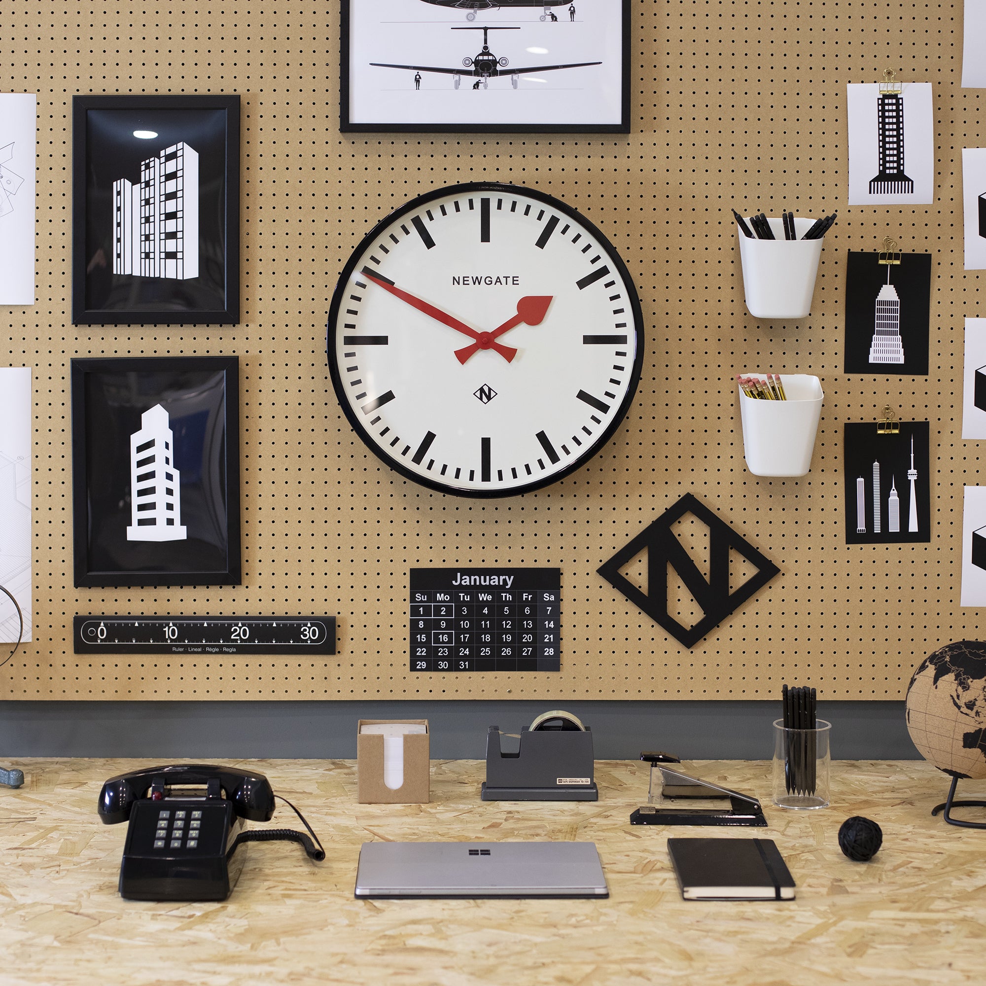 Black wall clock with white dial, red hour/minute hands, and bold hour markers.