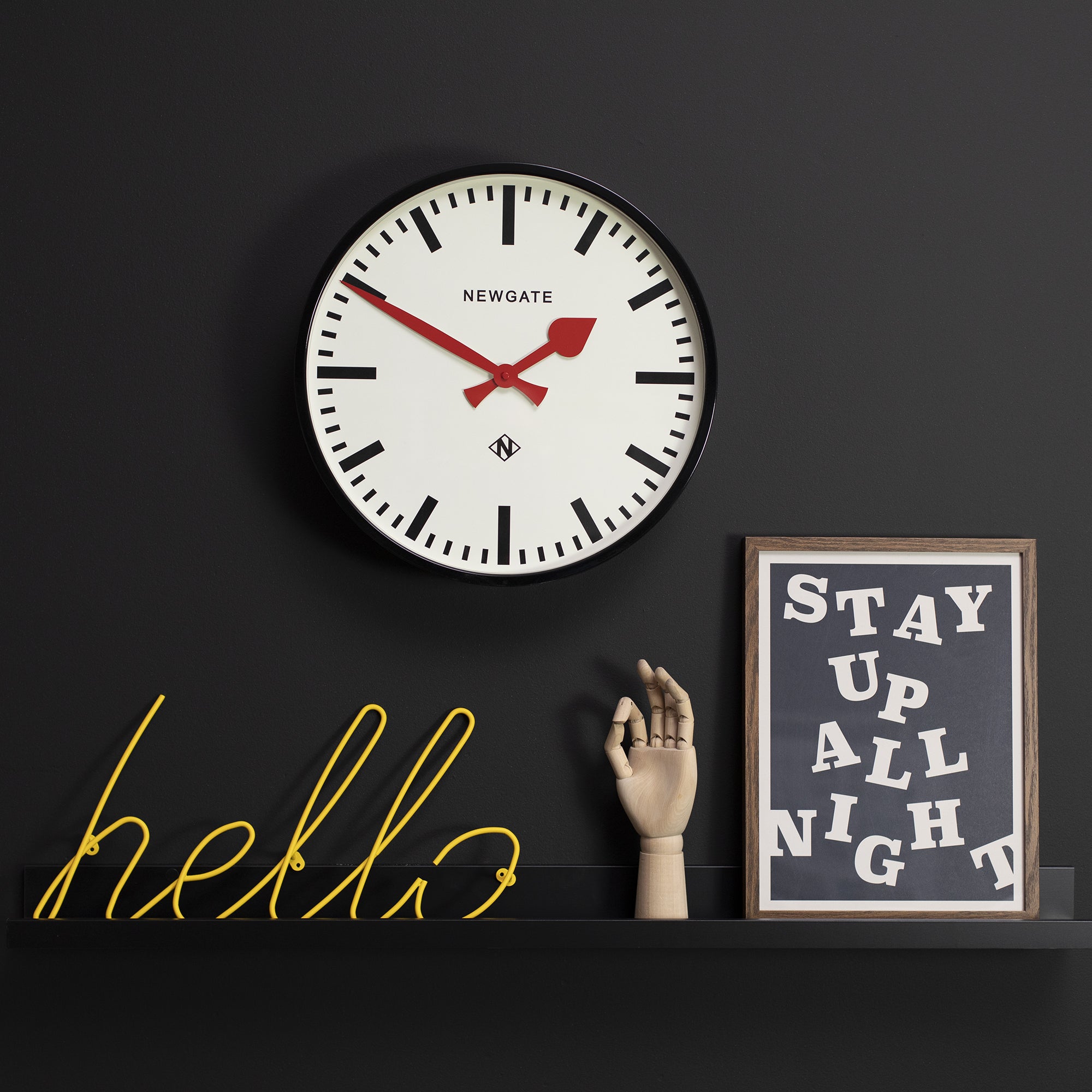 Black wall clock with white face and red hands, Newgate logo in the center.