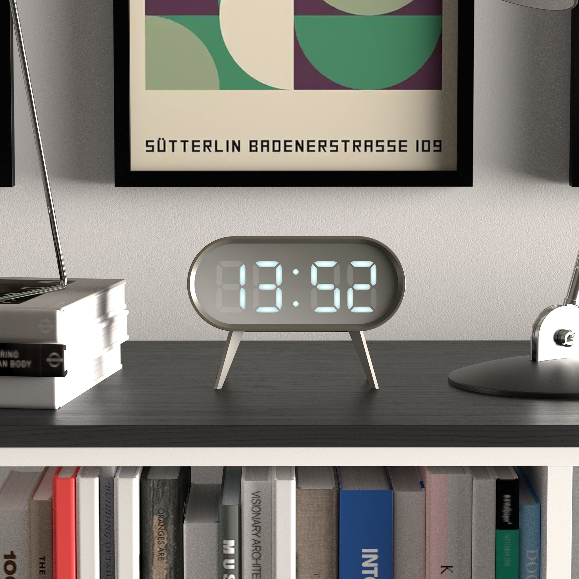 Grey LED alarm clock with digital time display 13:52, oval case on three legs