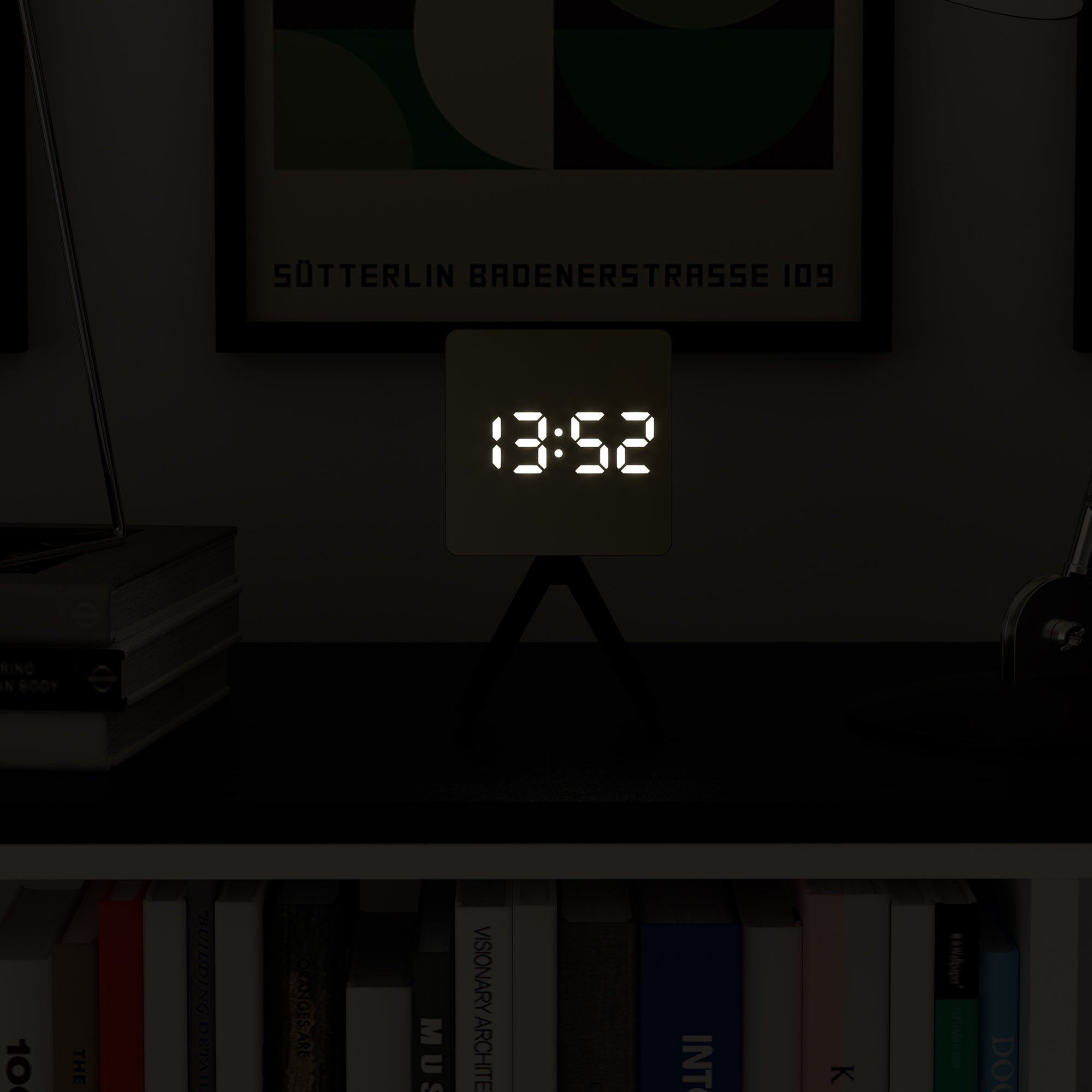 Black LED alarm clock with tripod stand and glowing time digits in dim light