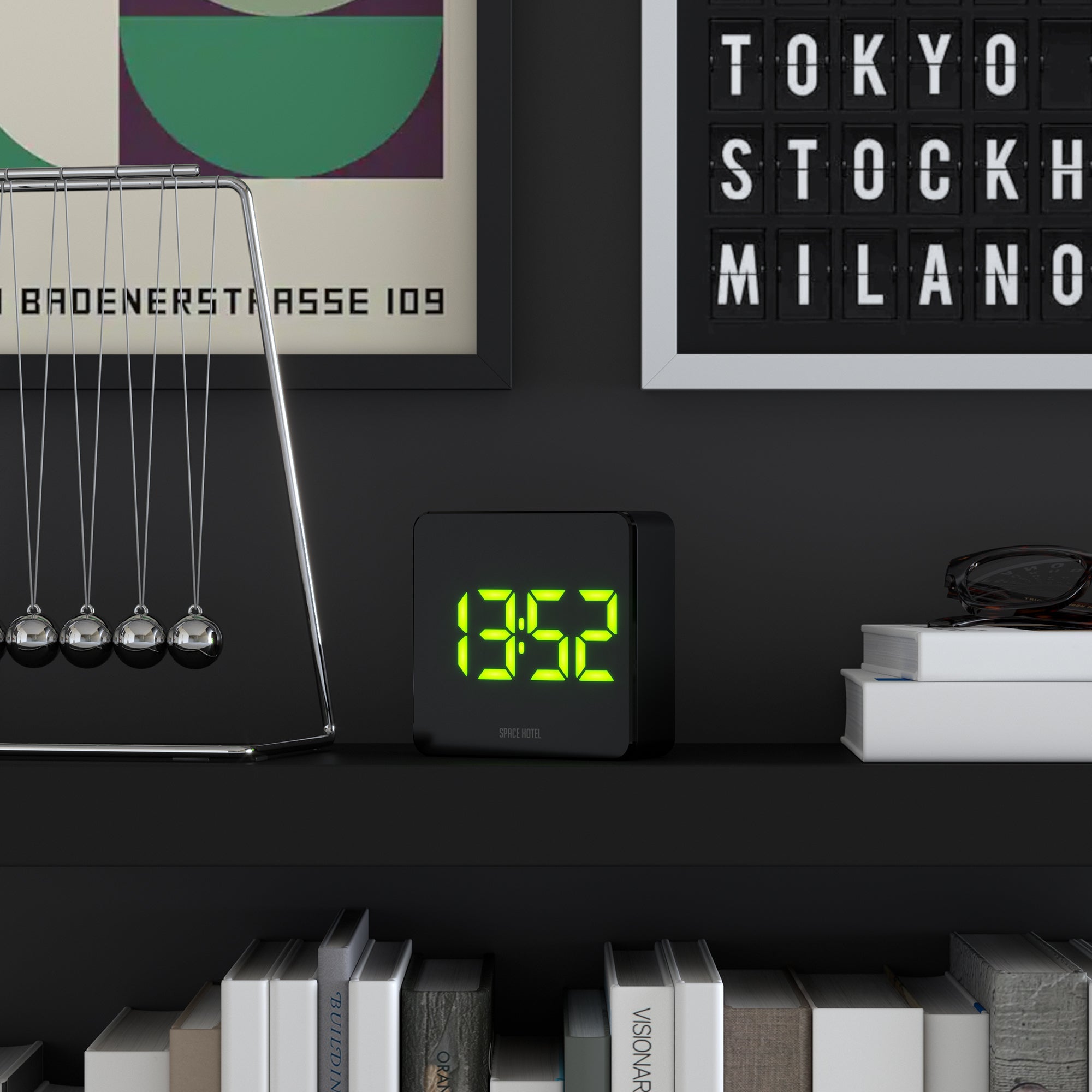Black alarm clock with green LED digits on tabletop, Space Hotel logo