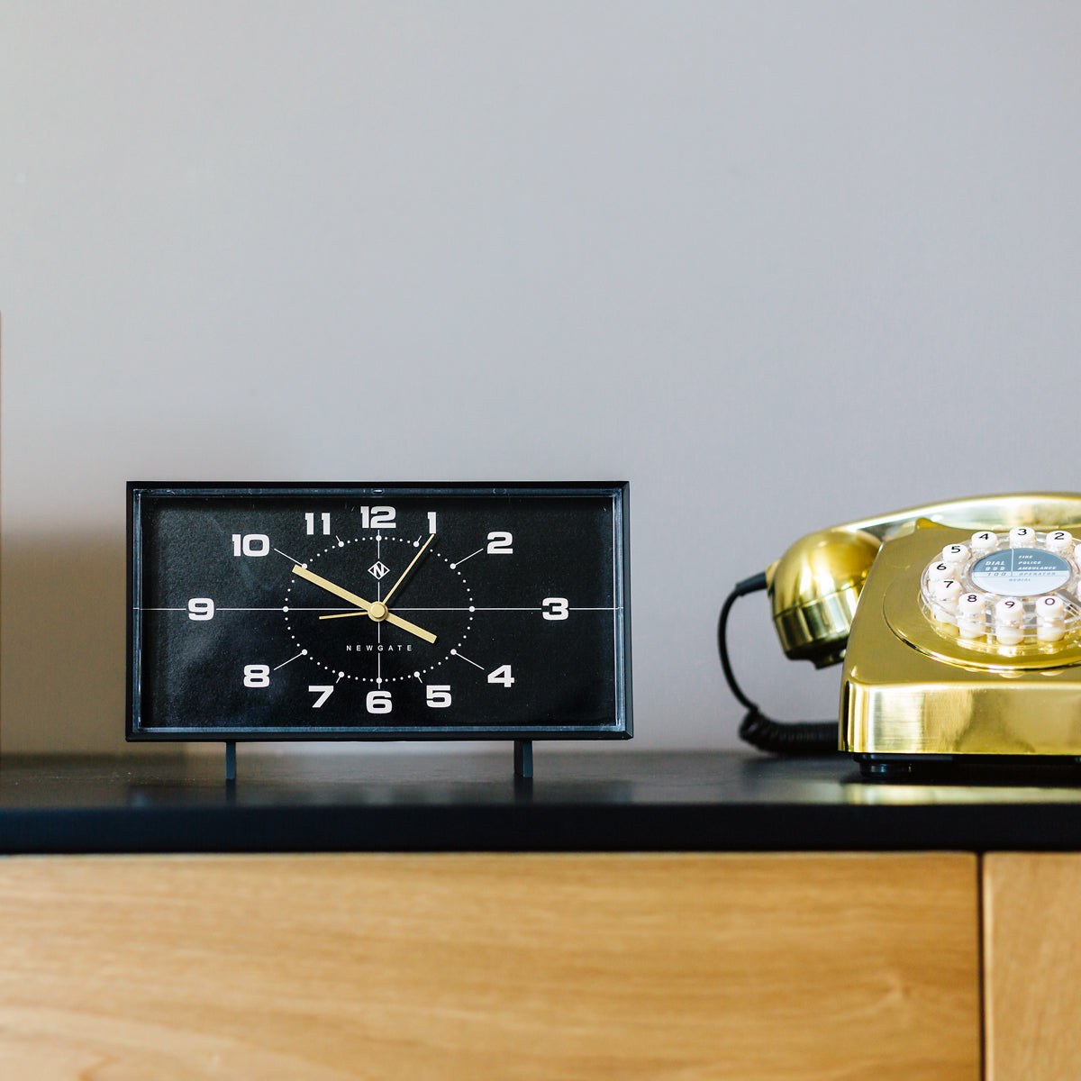 Black reverse-dial alarm clock with gold numerals on a table stand