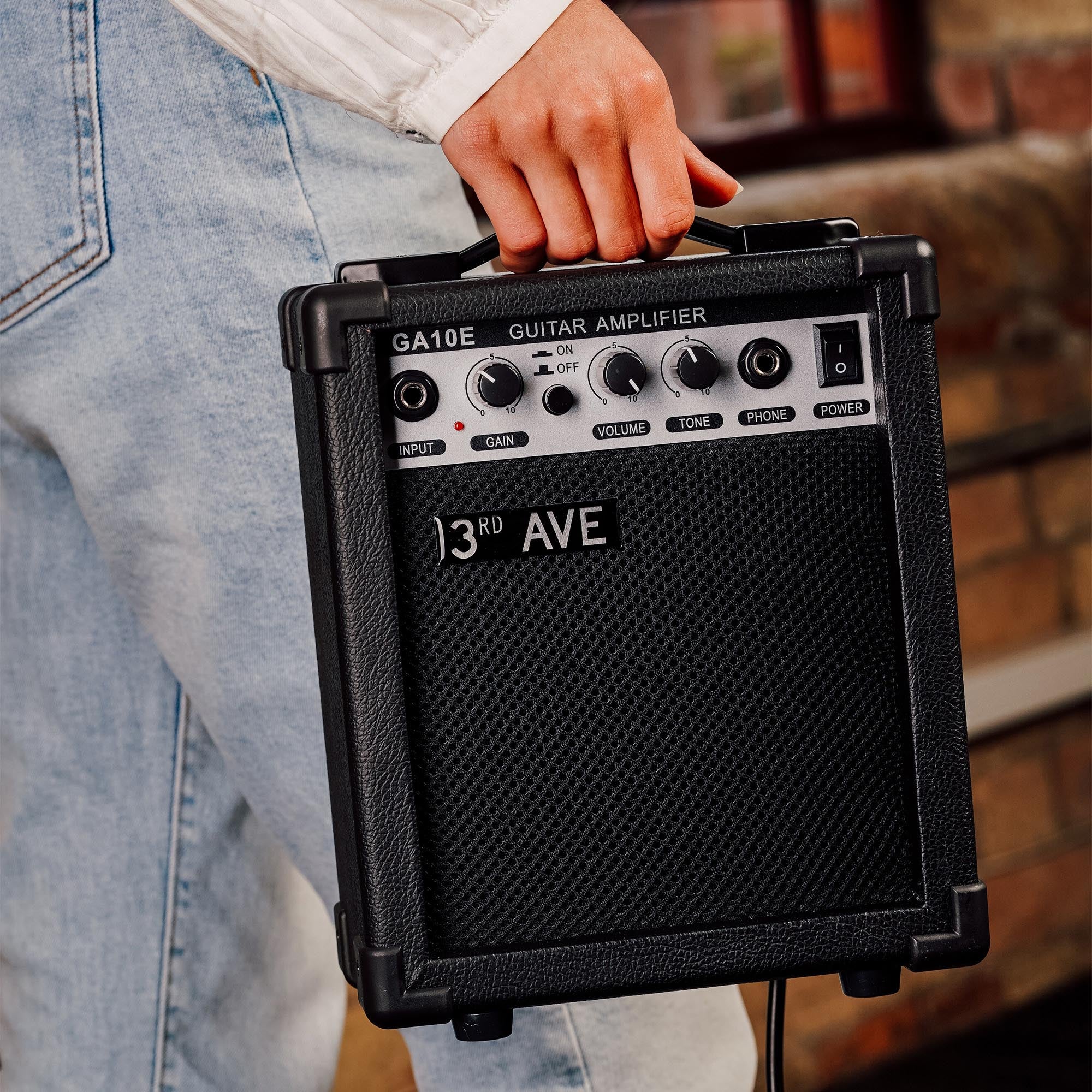 10W guitar amplifier front panel with control knobs and ports, held in hand, black
