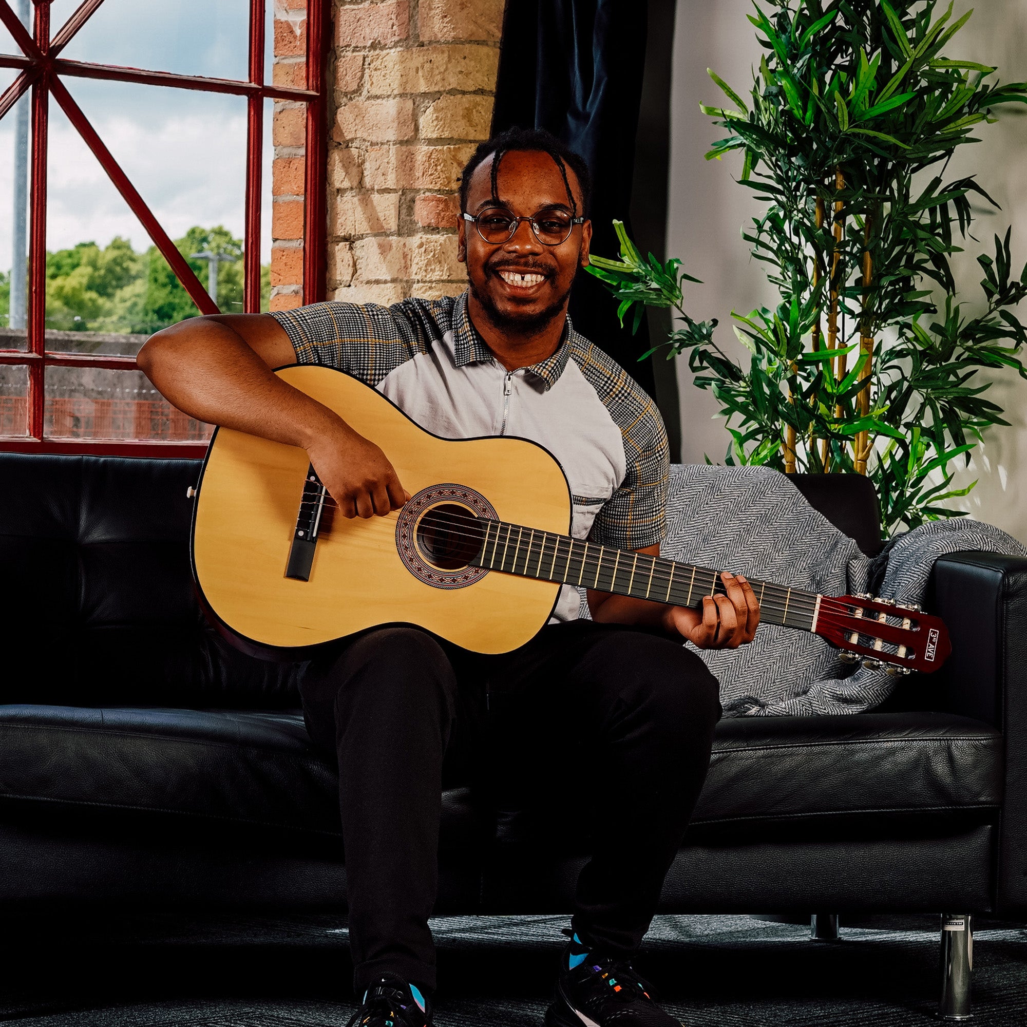 Natural classical guitar being played, with hand on fretboard and guitar body