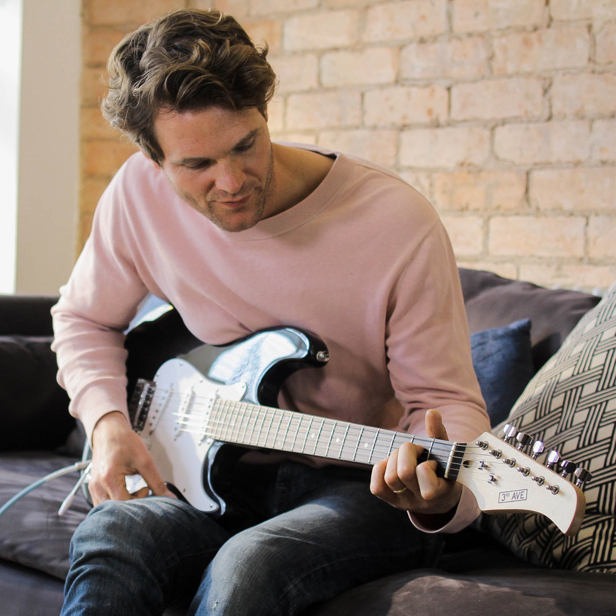 Light blue electric guitar being played while seated