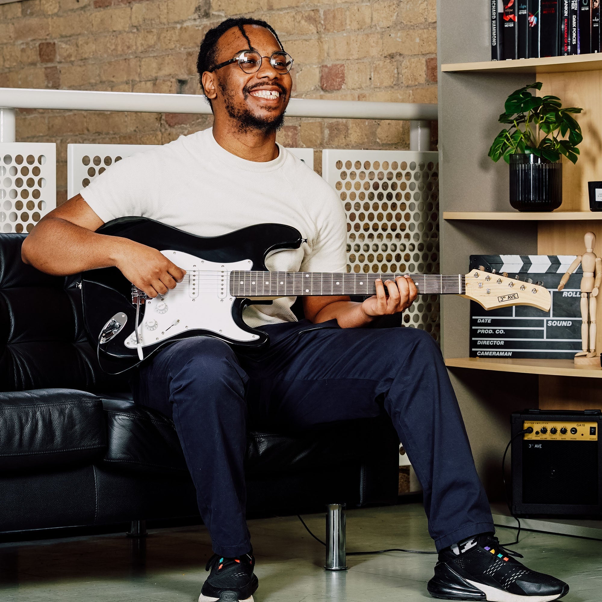 Black electric guitar held while seated on a couch