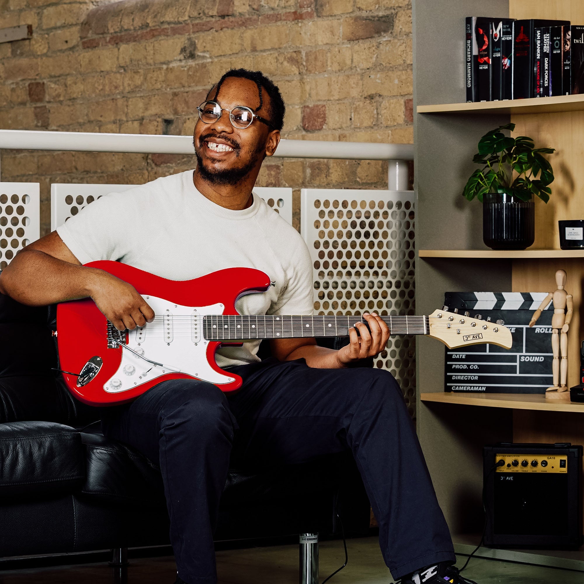 Red electric guitar on lap with white pickguard and chrome bridge
