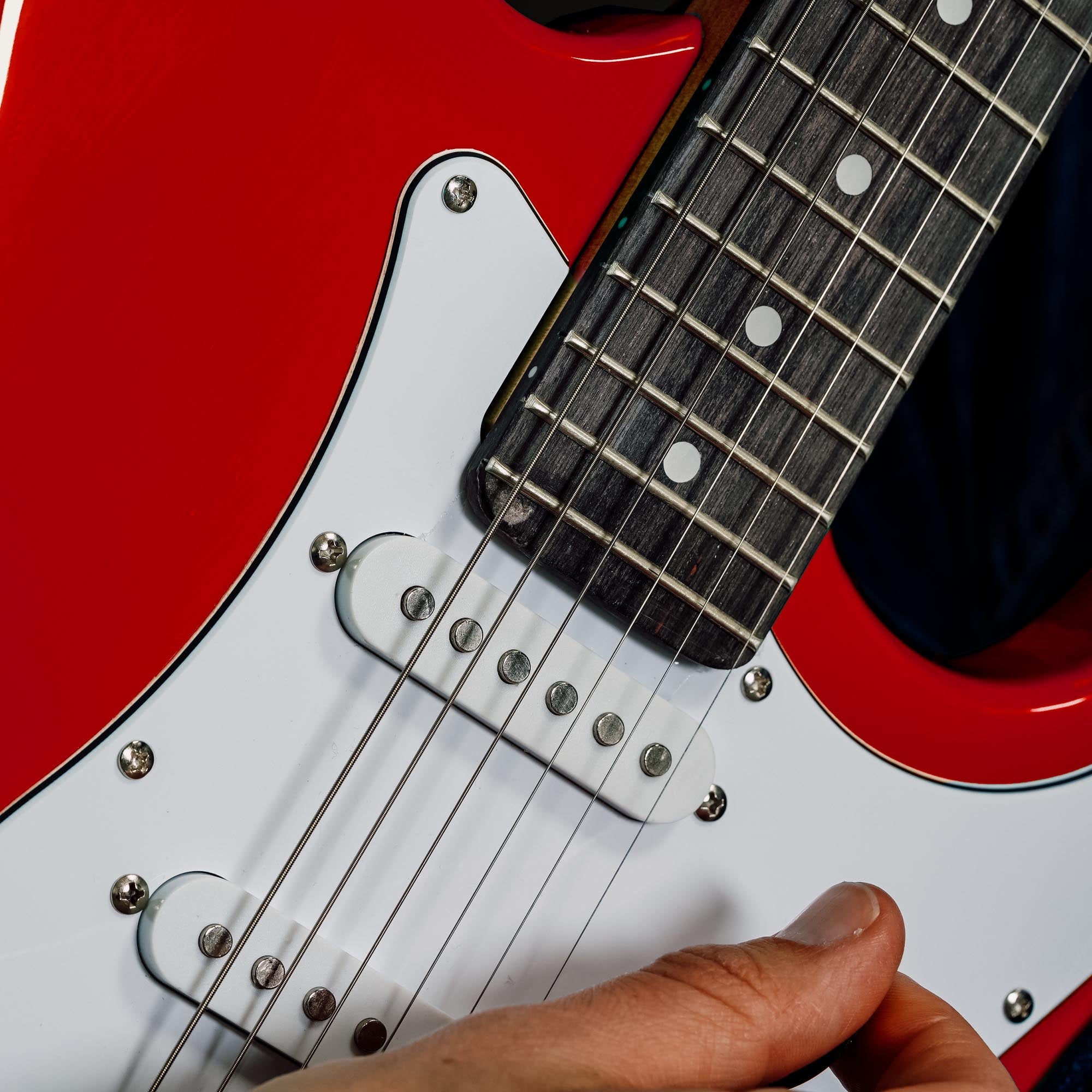 Red electric guitar close-up of bridge, strings, and pickups