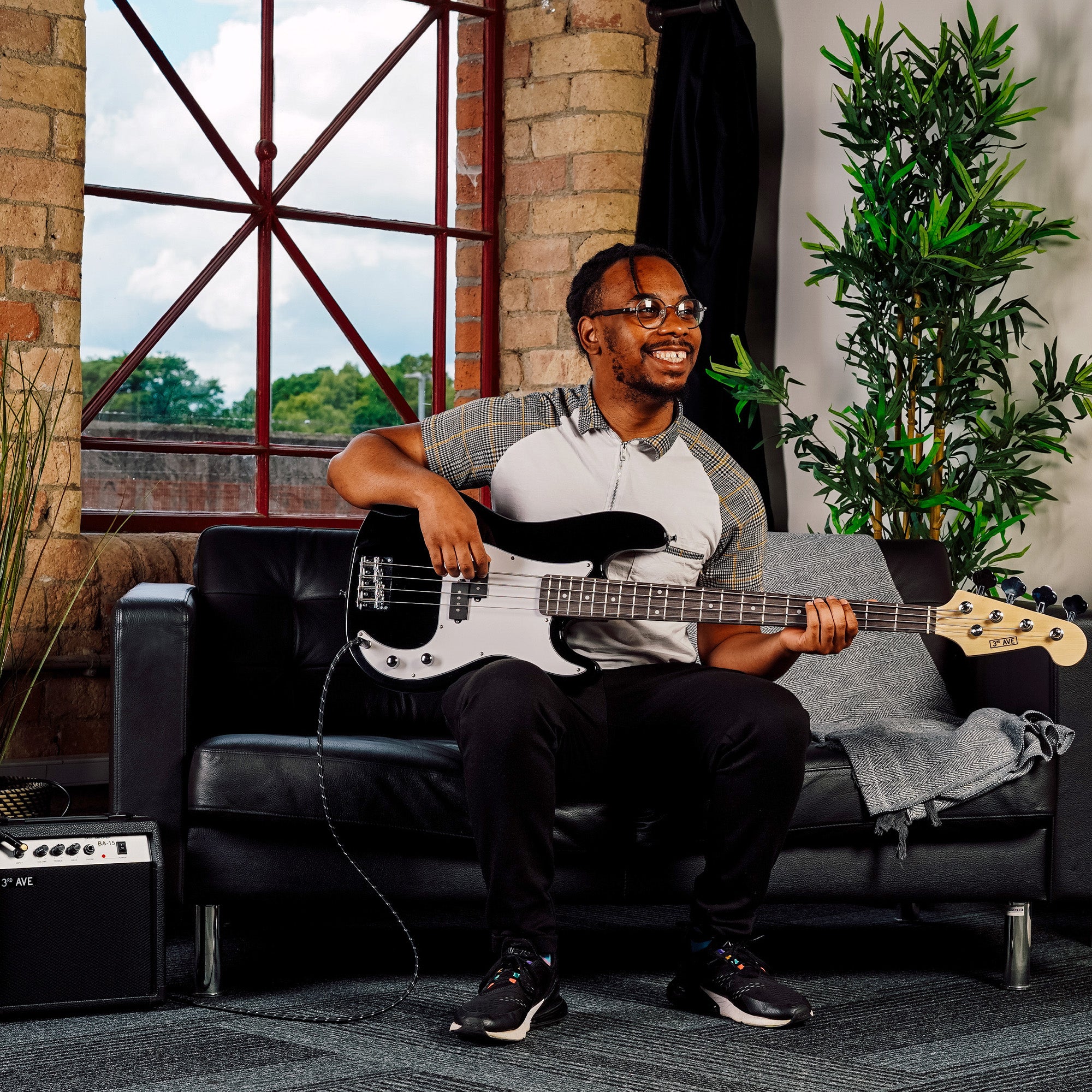 Black bass guitar played while seated on a couch