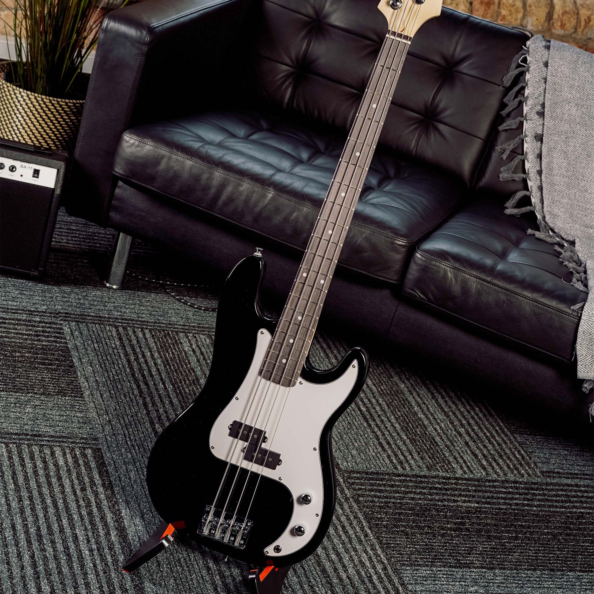 Black electric bass guitar with white pickguard on a couch