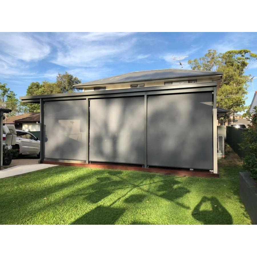 Outdoor roller sun screen blind with dark gray fabric panels on an attached frame