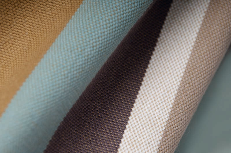 Rectangular cushion cover close-up: woven stripes in blue, tan, white and dark brown