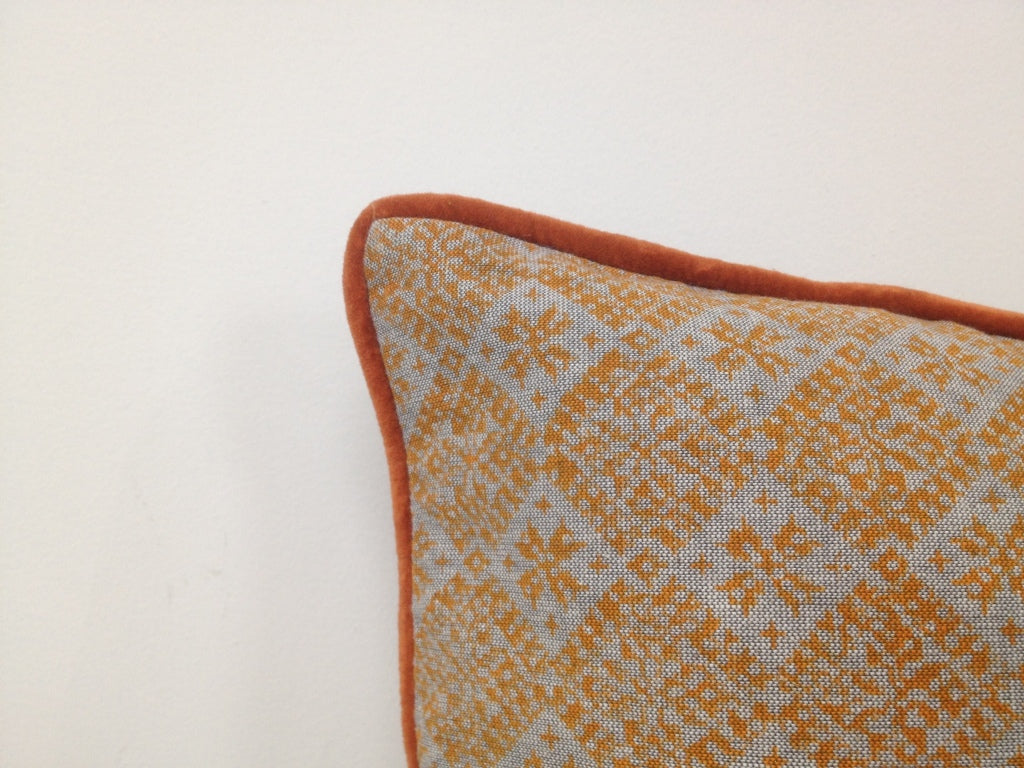 Cushion cover corner with geometric pattern and orange piping trim