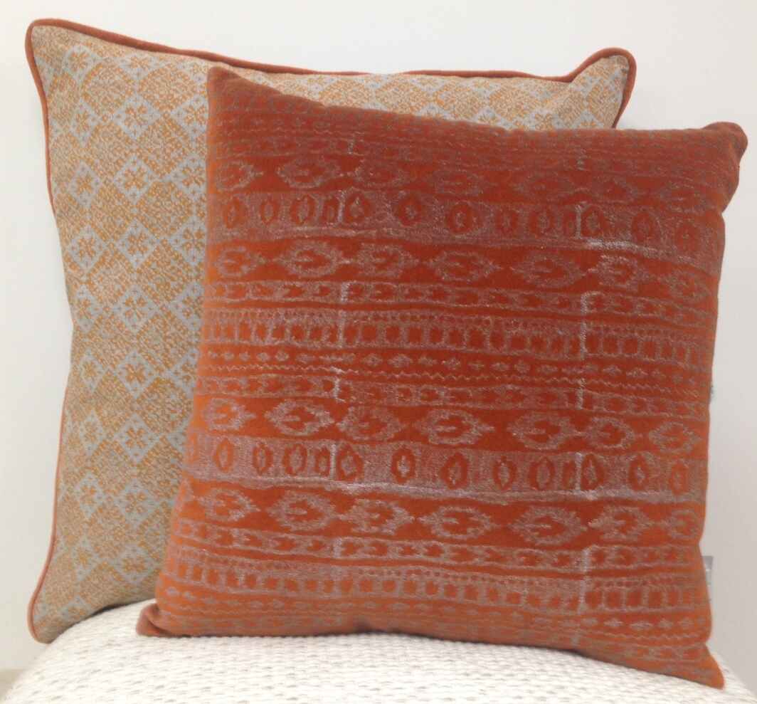 Cushion cover set with orange patterned front and beige geometric cover behind