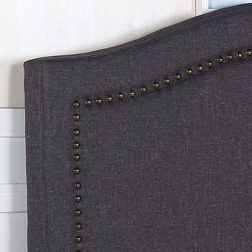 Linen headboard panel corner with dark fabric and small brass nailhead buttons