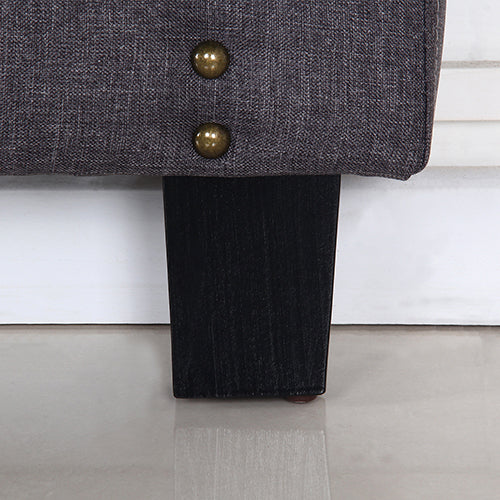Square wood headboard legs with brass nailhead detail on charcoal upholstery