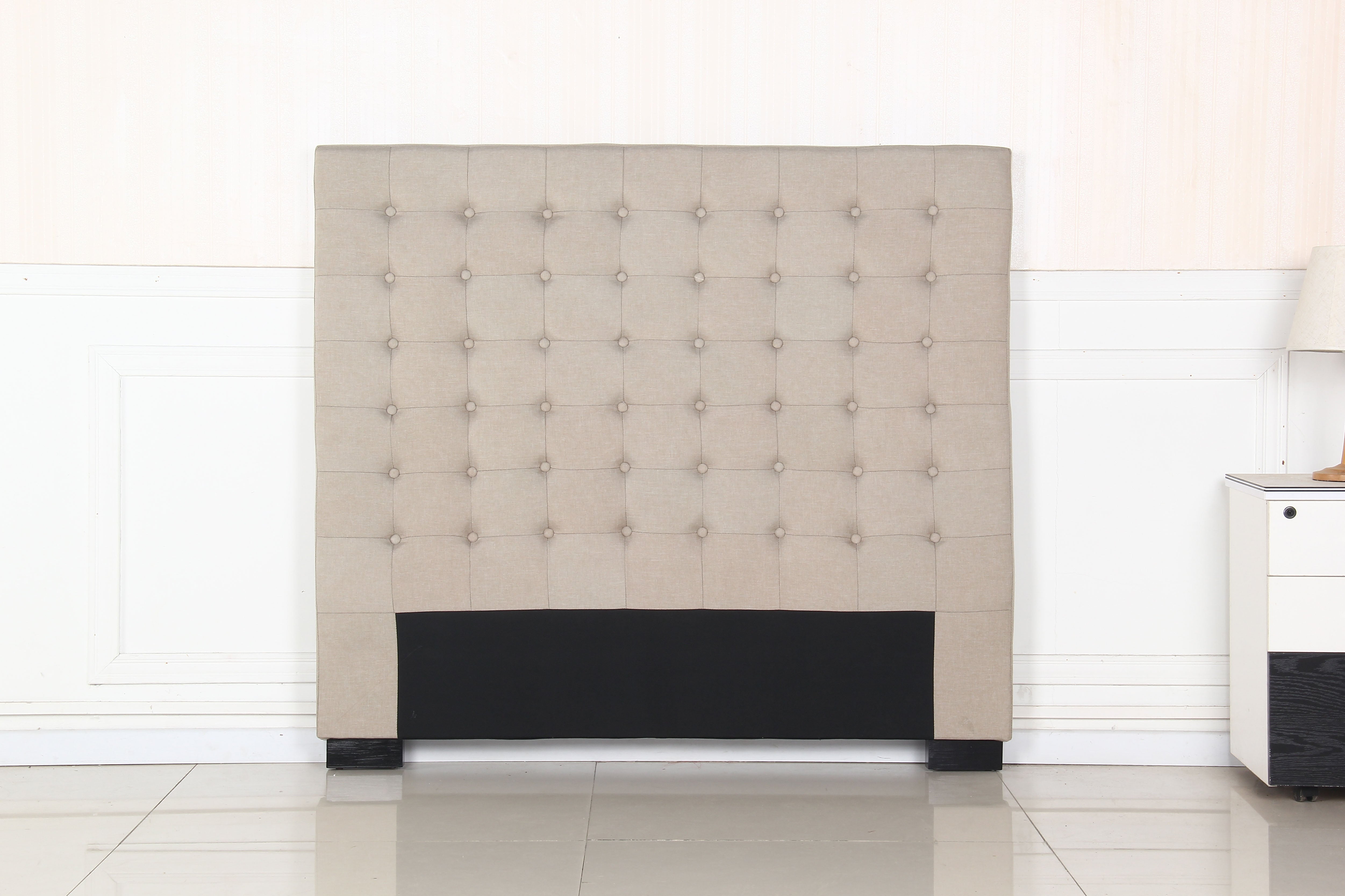 Beige upholstered tufted headboard with round buttons and dark base